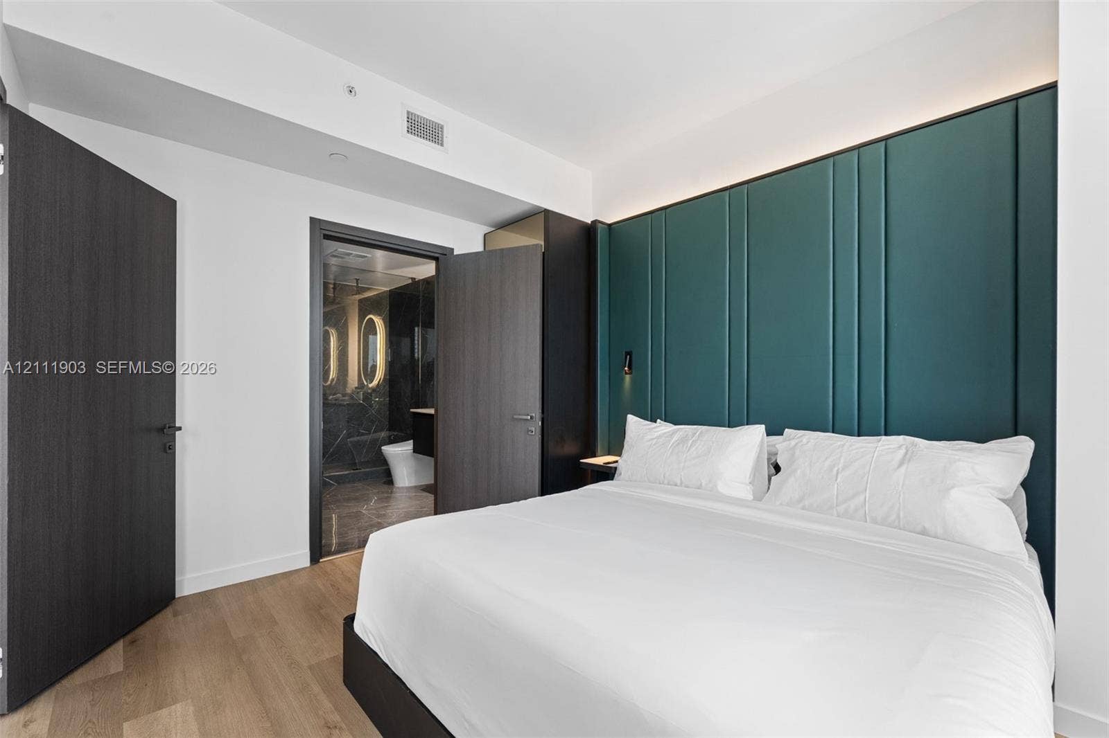 20 NE 11th Street, #4308, Miami, FL 33132 Floor-to-ceiling teal upholstered accent wall with integrated lighting, wood-finish flooring, and dark wood-finish interior doors