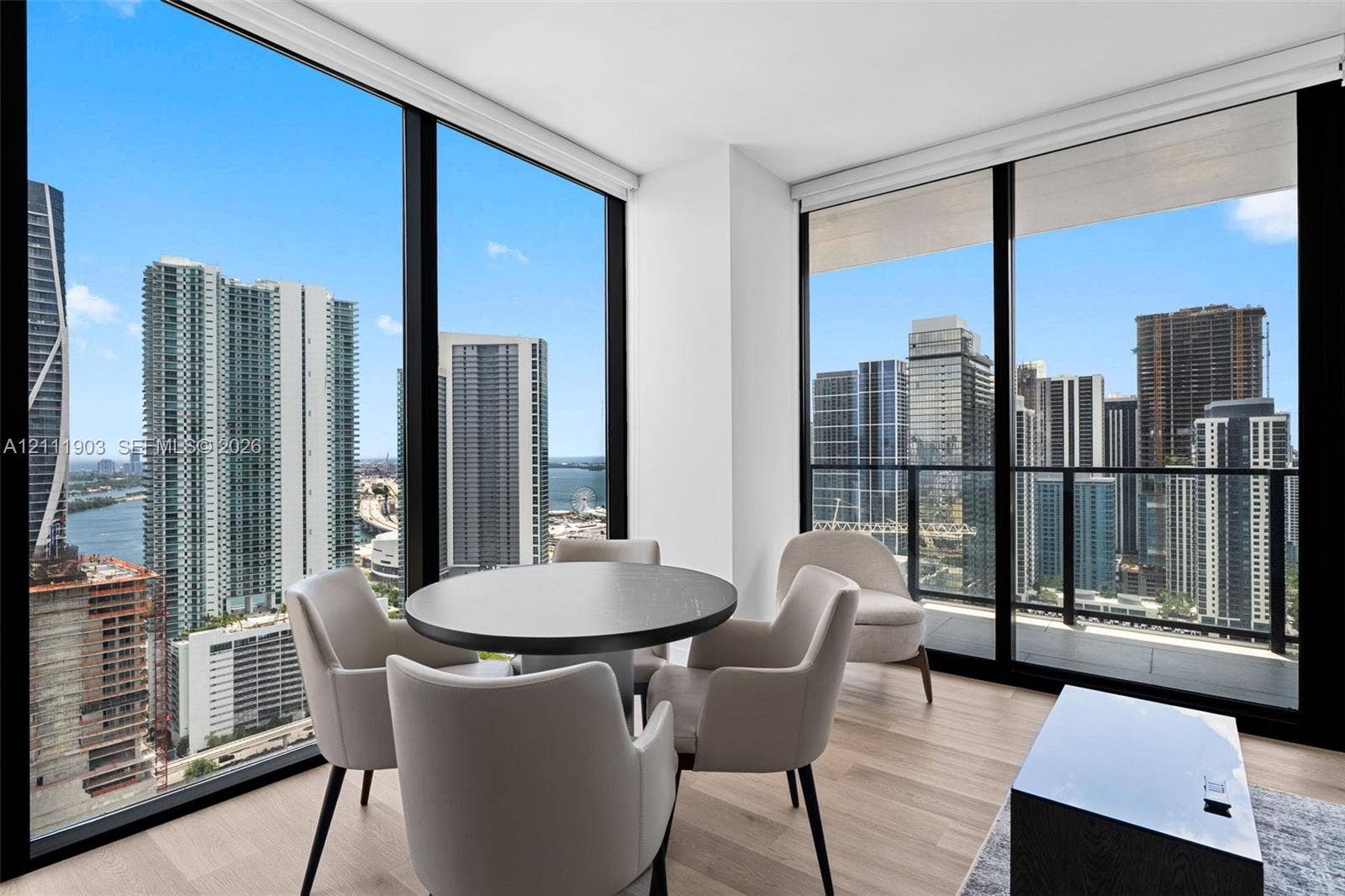 20 NE 11th Street, #4308, Miami, FL 33132 Floor-to-ceiling windows, wood-finish flooring, and a private balcony featuring a glass railing with urban skyline scenery
