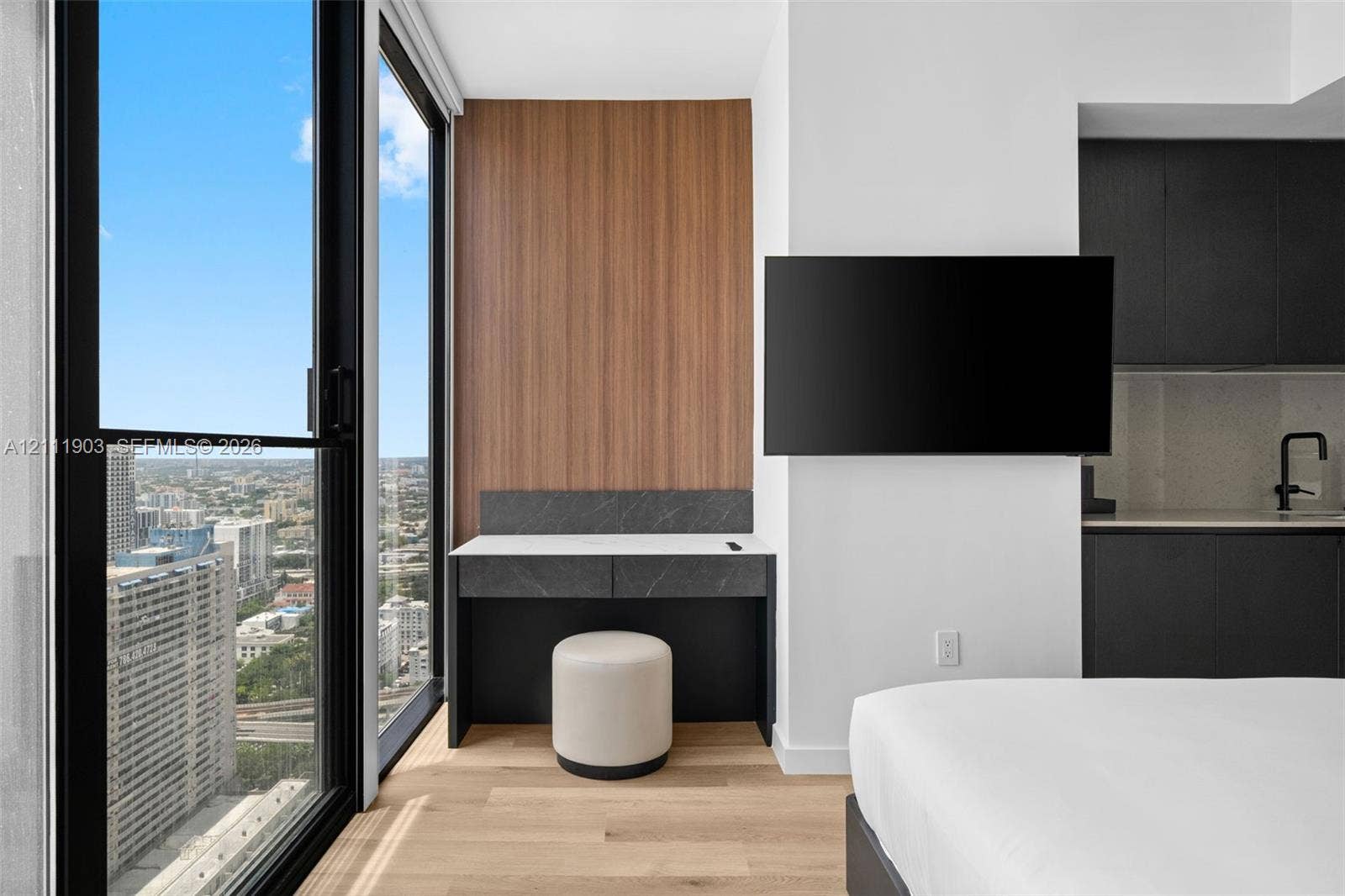 20 NE 11th Street, #4308, Miami, FL 33132 Floor-to-ceiling windows, wood-finish flooring, built-in desk with stone surface, and matte black kitchen fixtures