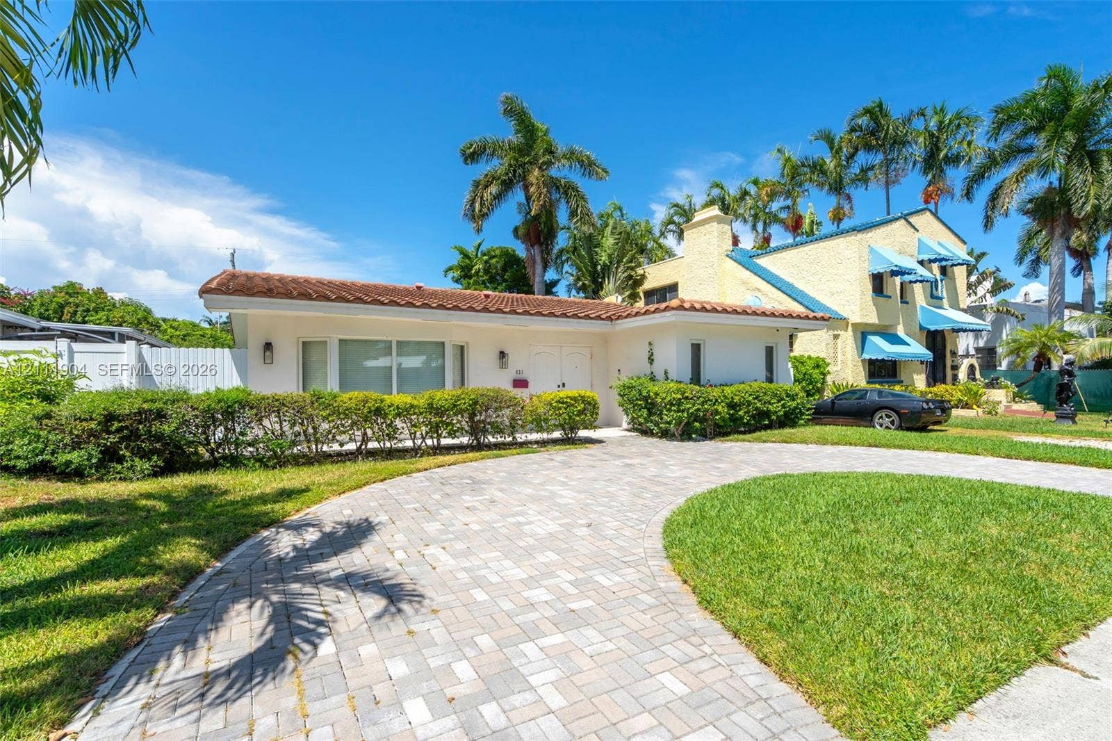 821 Harrison Street, Hollywood, FL 33019 Stucco exterior featuring a terracotta tile roof, brick-paver circular driveway, and manicured landscaping