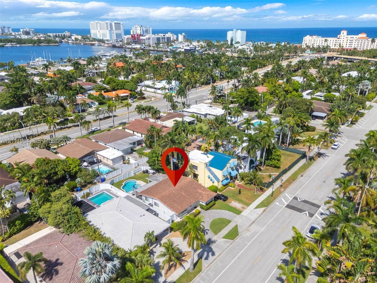 821 Harrison Street, Hollywood, FL 33019 Aerial perspective of a property featuring a multi-pitched roofline, paved driveway, landscaped grounds, and proximity to coastal waterfront and urban centers