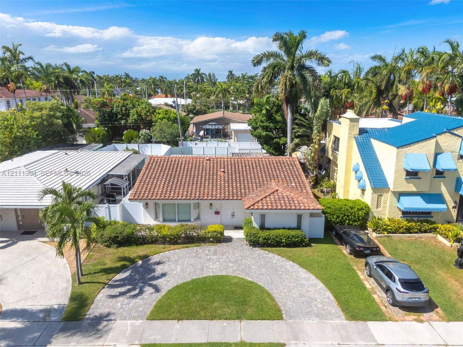 821 Harrison Street, Hollywood, FL 33019 Single-story residence featuring a clay tile roof, a curved paver driveway, and landscaped front grounds