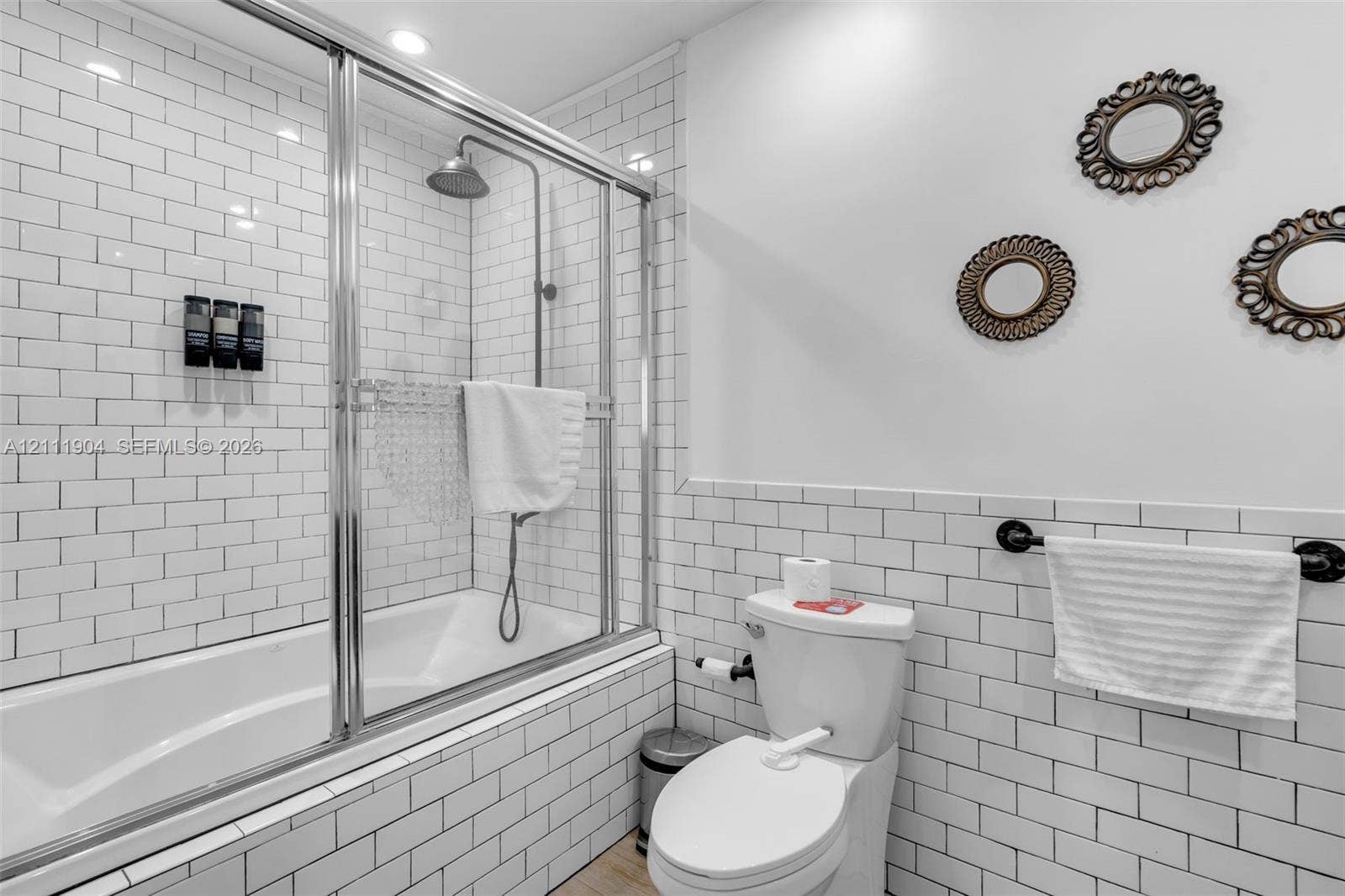 821 Harrison Street, Hollywood, FL 33019 Subway tile wall treatments, chrome-framed glass shower enclosure, deep soaking tub, and wall-mounted metal towel rack
