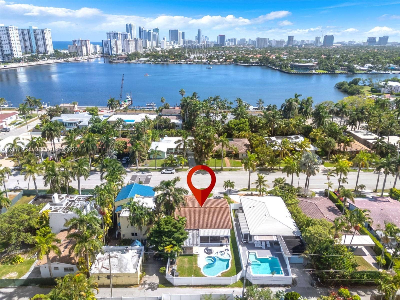 821 Harrison Street, Hollywood, FL 33019 Residential property featuring a shingle-style roof, private swimming pool, concrete patio, and fenced backyard, situated within a coastal tropical landscape
