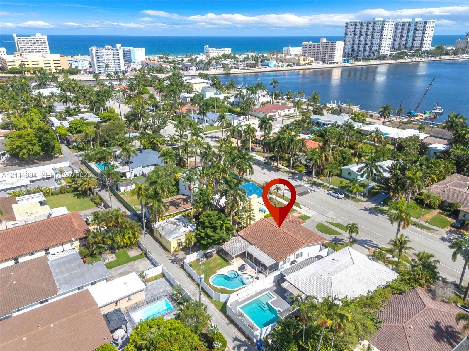 821 Harrison Street, Hollywood, FL 33019 Aerial perspective of a single-story residence featuring a tile roof, an integrated pool and spa, a screened-in patio, and privacy fencing