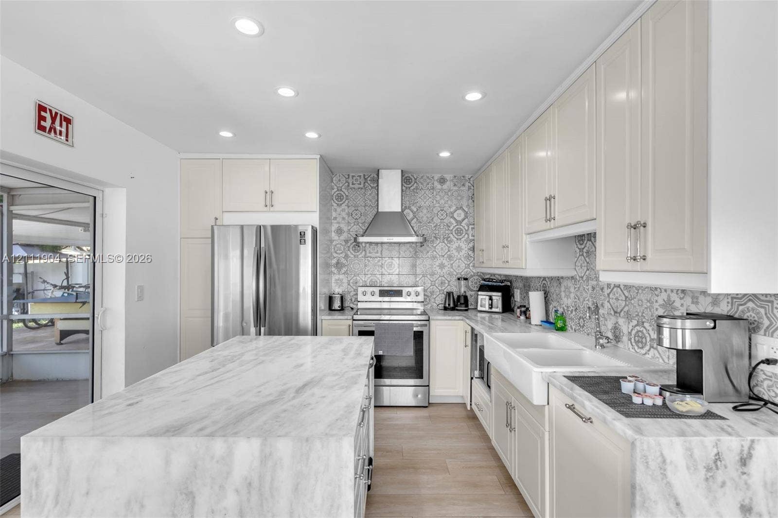 821 Harrison Street, Hollywood, FL 33019 Kitchen featuring stone-topped central island, patterned tile backsplash, apron-front sink, stainless steel appliances, and recessed lighting