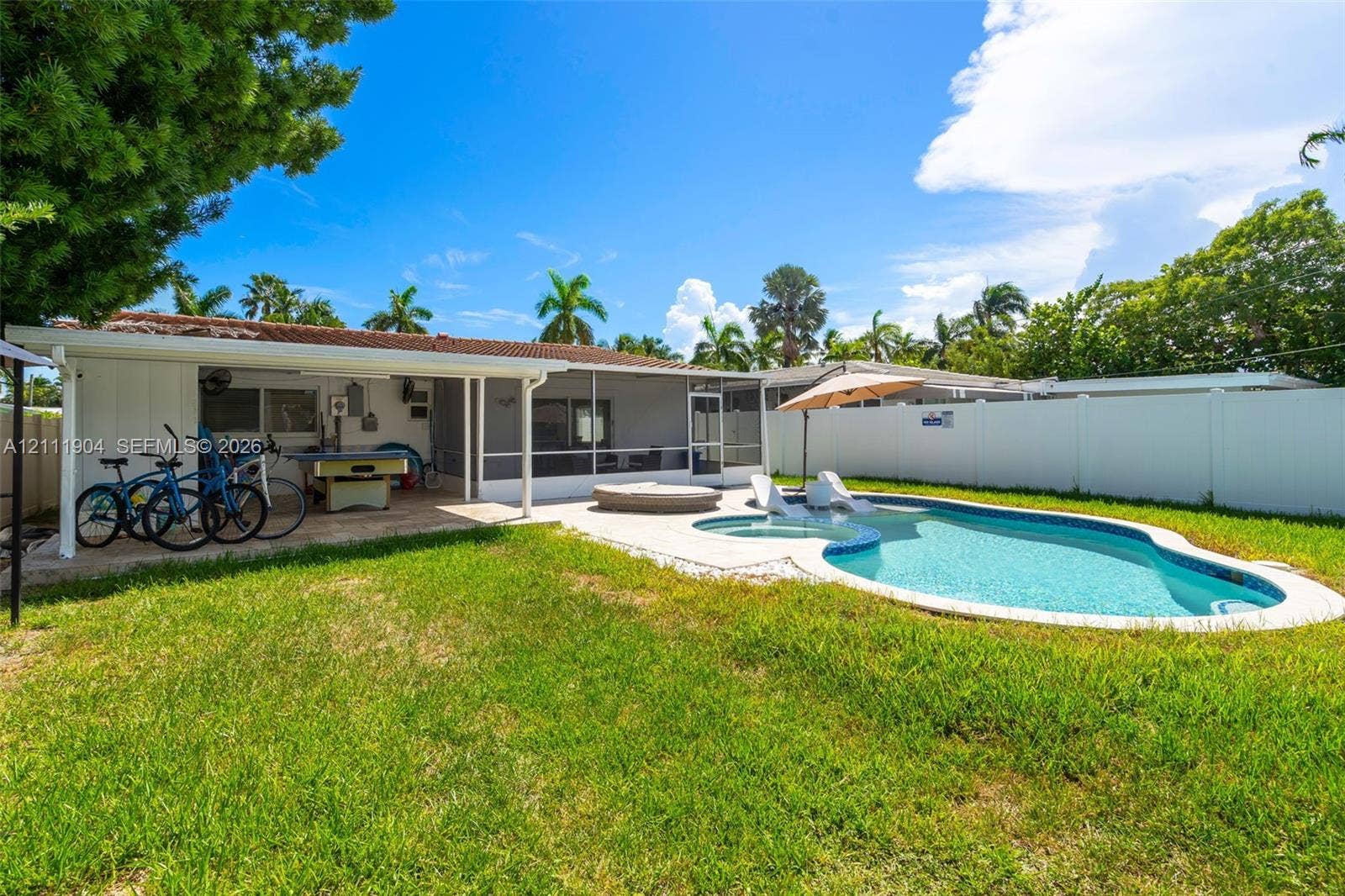 821 Harrison Street, Hollywood, FL 33019 Outdoor living area featuring a covered lanai, screen-enclosed patio, in-ground pool with integrated spa, and full privacy fencing