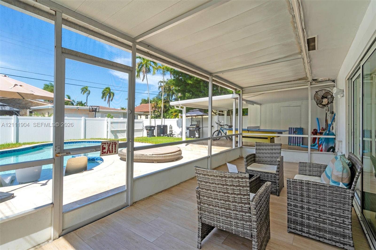 821 Harrison Street, Hollywood, FL 33019 Screened-in lanai featuring wood-finish tile flooring, a metal frame enclosure, and a direct entrance to an outdoor swimming pool and concrete patio area