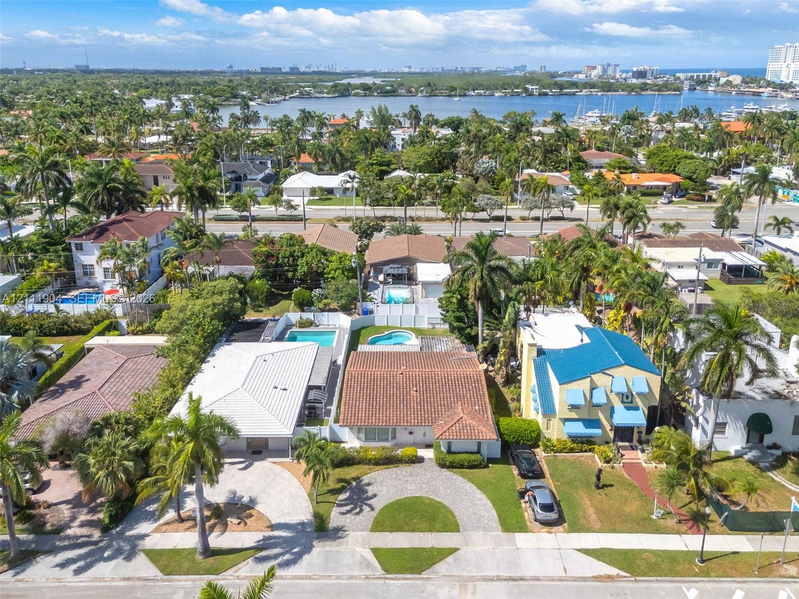 821 Harrison Street, Hollywood, FL 33019 Residential lot featuring a circular paved driveway, mature palm trees, and an in-ground swimming pool enclosed by privacy fencing