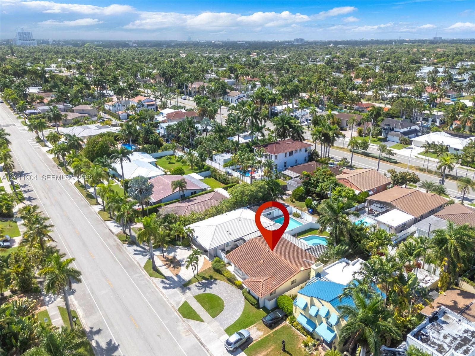 821 Harrison Street, Hollywood, FL 33019 Aerial perspective of a residence featuring a tile roof, paved circular driveway, enclosed rear patio, and a private swimming pool, situated within a coastal tropical landscape
