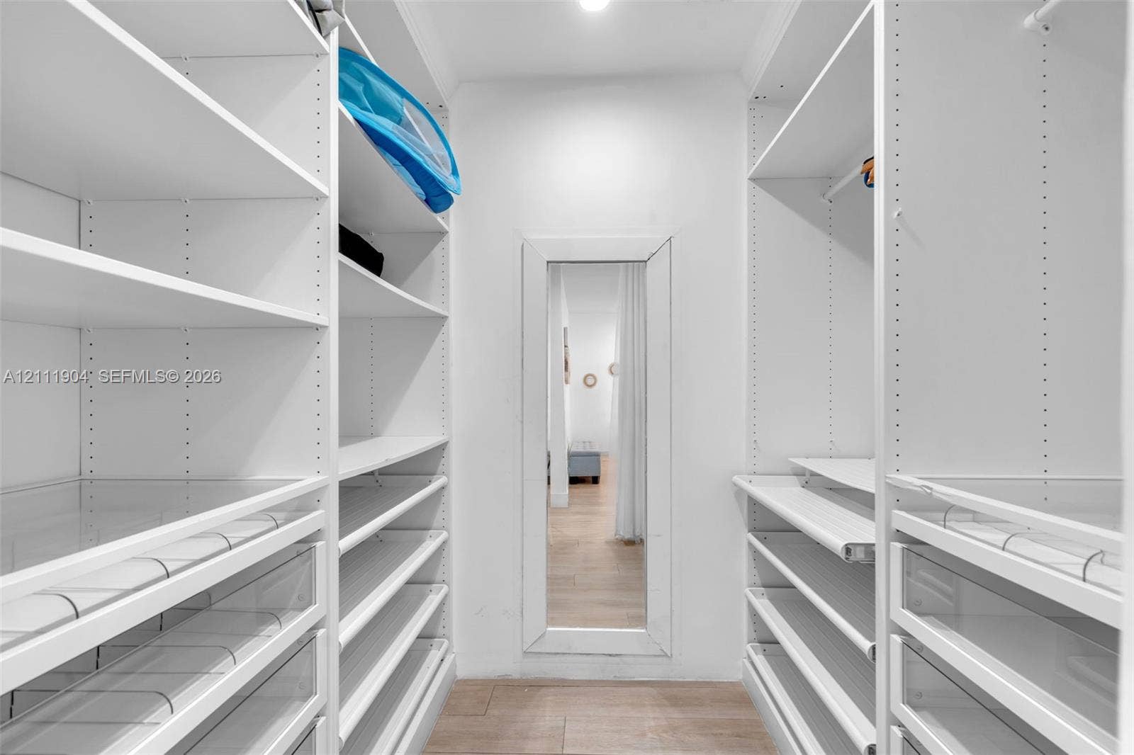 821 Harrison Street, Hollywood, FL 33019 Walk-in closet featuring floor-to-ceiling white built-in shelving, integrated pull-out drawers, hanging rods, and a full-length wall-mounted mirror
