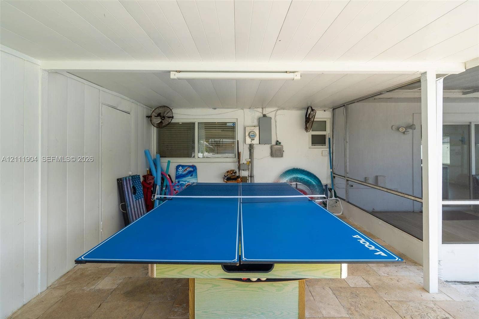 821 Harrison Street, Hollywood, FL 33019 Covered patio featuring stone-tile flooring, screen enclosure, ceiling-mounted fans, and white vertical panel siding
