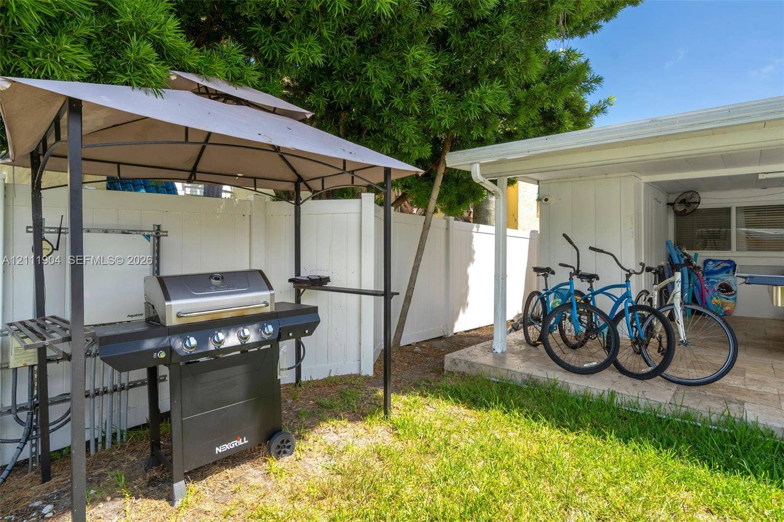 821 Harrison Street, Hollywood, FL 33019 Private outdoor area featuring a white vinyl privacy fence, a concrete patio, and an integrated metal gazebo structure