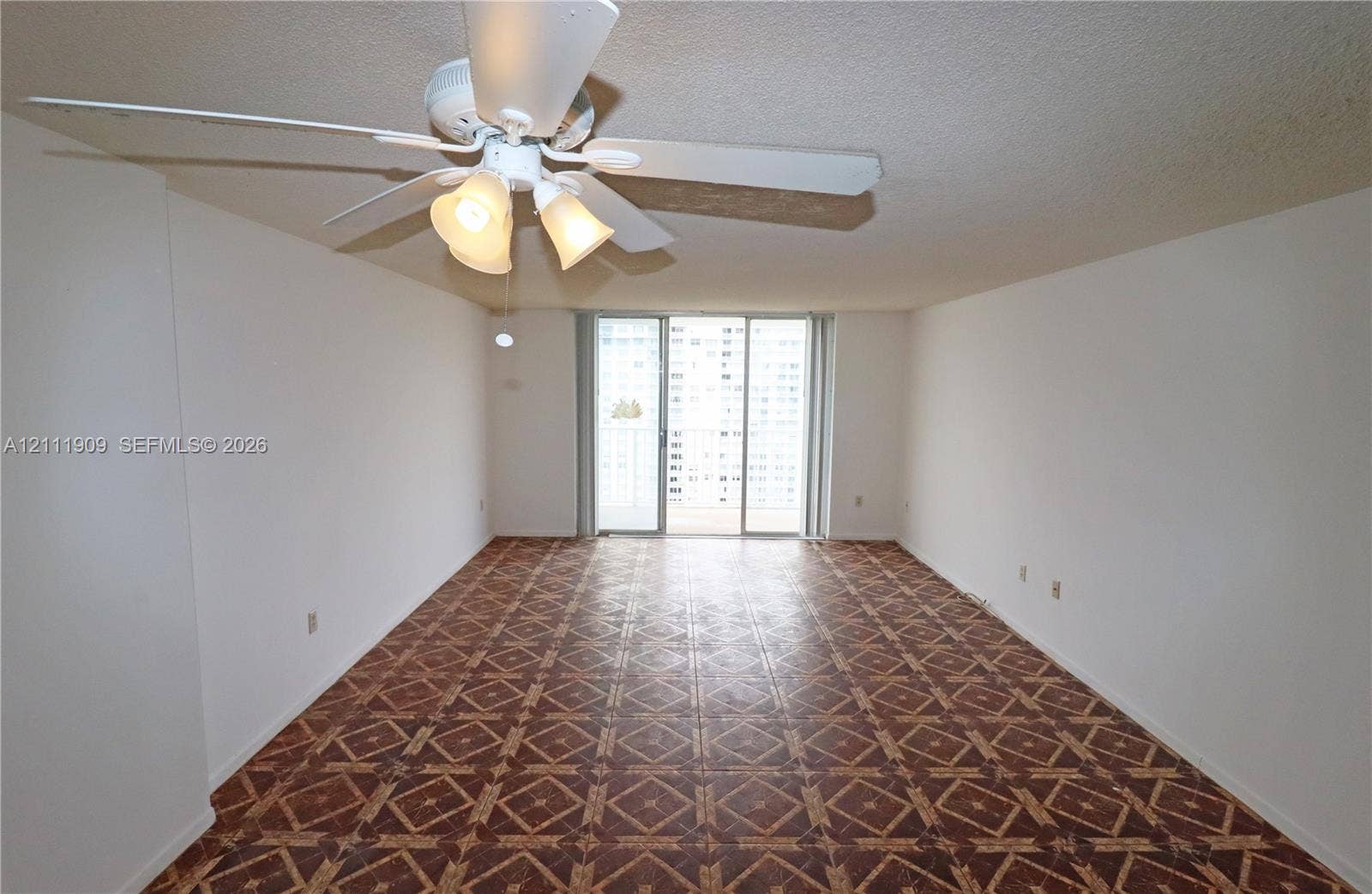 2851 NE 183rd Street, #1708E, Aventura, FL 33160 Interior space featuring geometric-patterned flooring, a ceiling fan with integrated lighting, and sliding glass doors leading to an exterior balcony