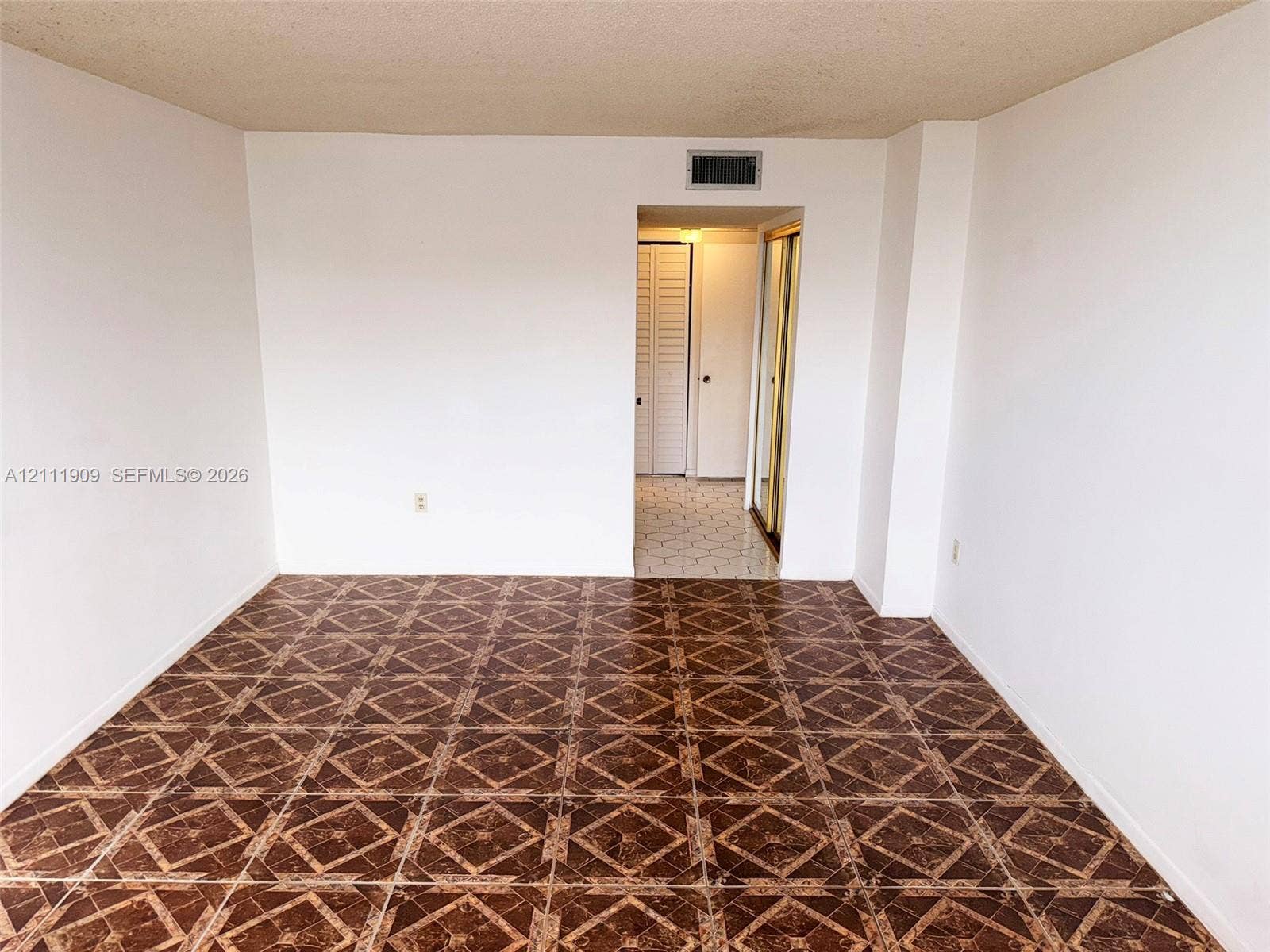 2851 NE 183rd Street, #1708E, Aventura, FL 33160 Interior room featuring dark, patterned tile flooring and smooth, white-painted walls
