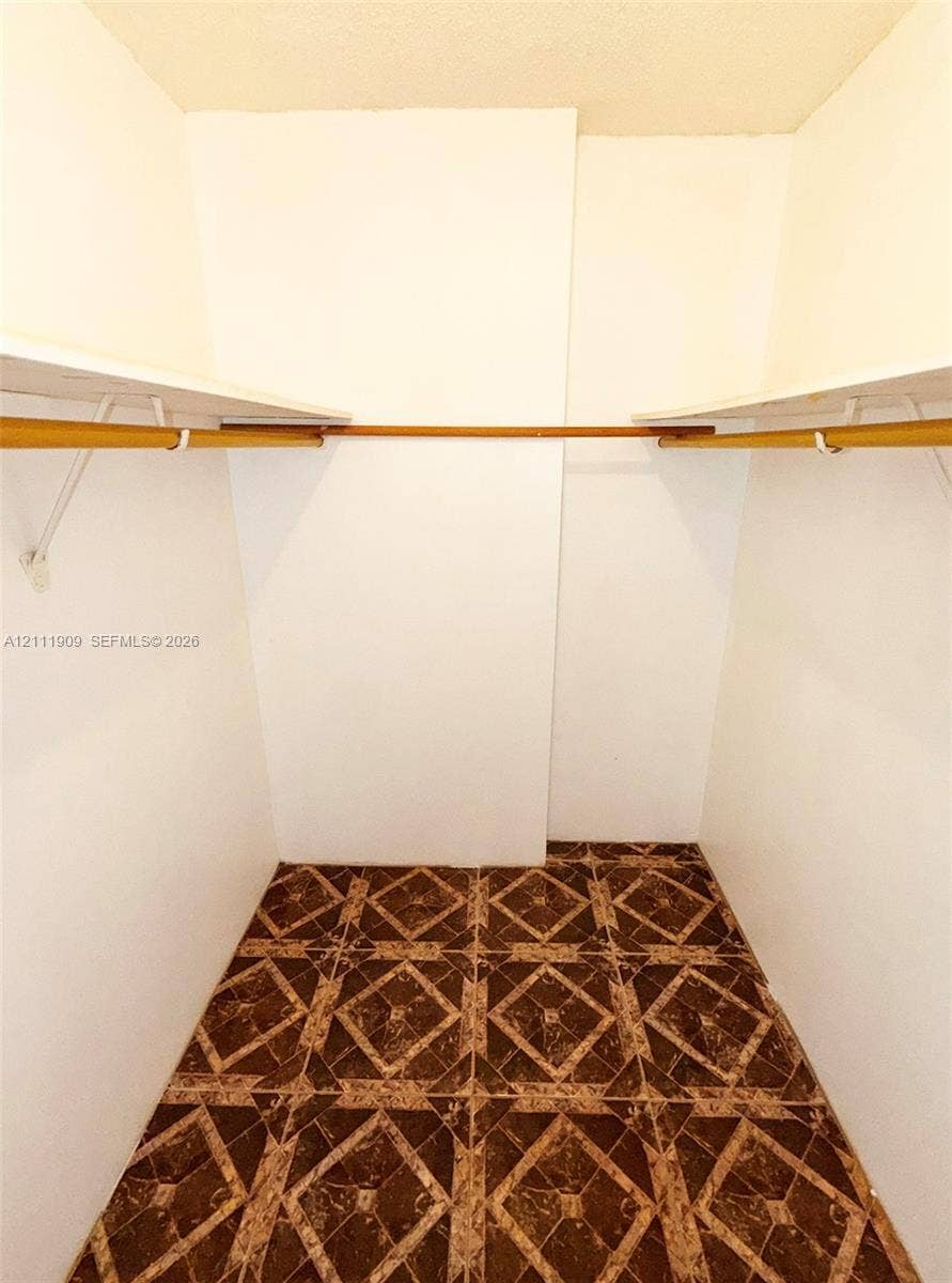 2851 NE 183rd Street, #1708E, Aventura, FL 33160 Storage space featuring white walls, upper shelving, and installed hanging rods over geometric-patterned tile flooring