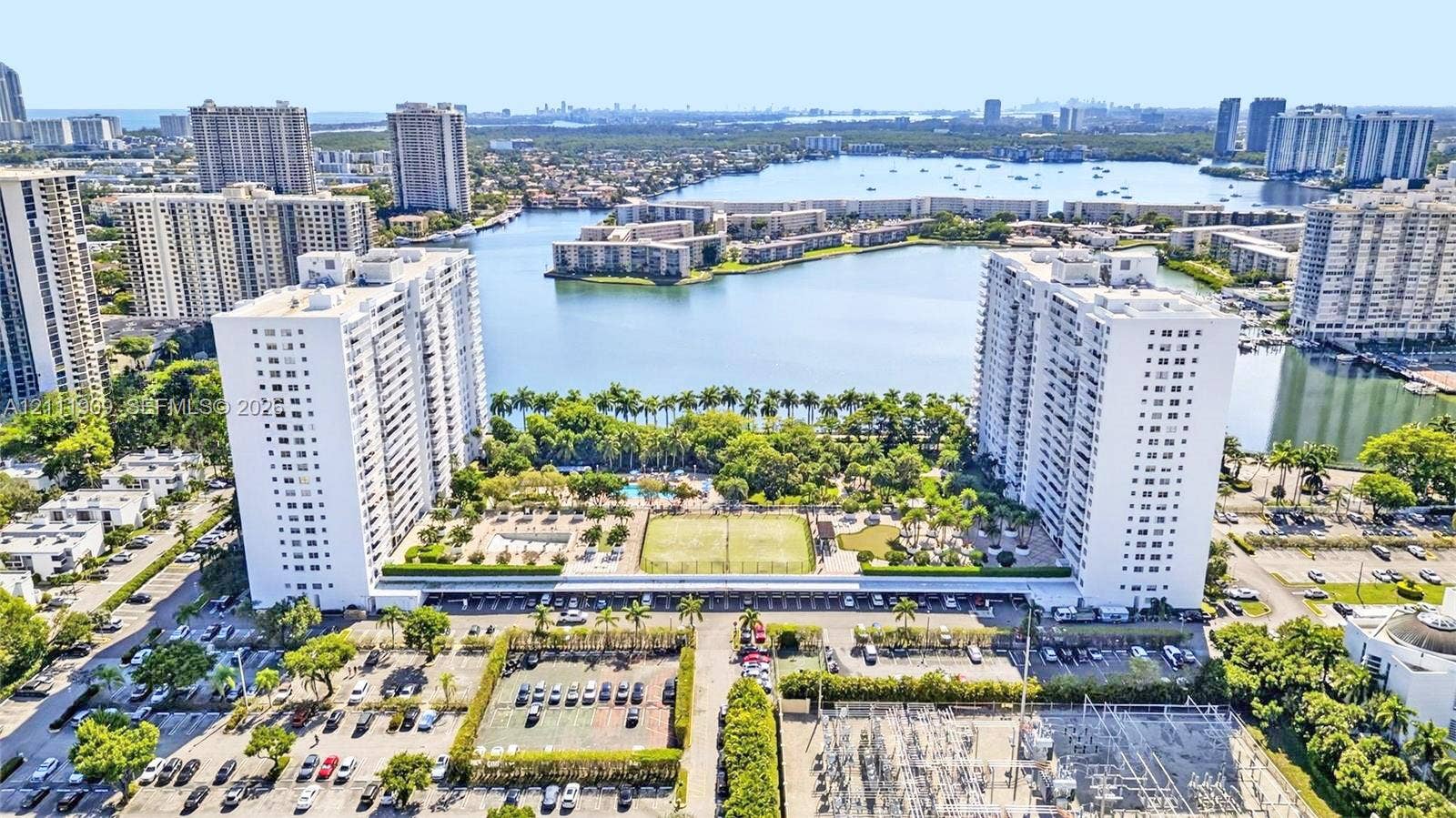 2851 NE 183rd Street, #1708E, Aventura, FL 33160 Aerial perspective featuring waterfront high-rise buildings, tennis courts, an outdoor swimming pool, and dedicated parking areas