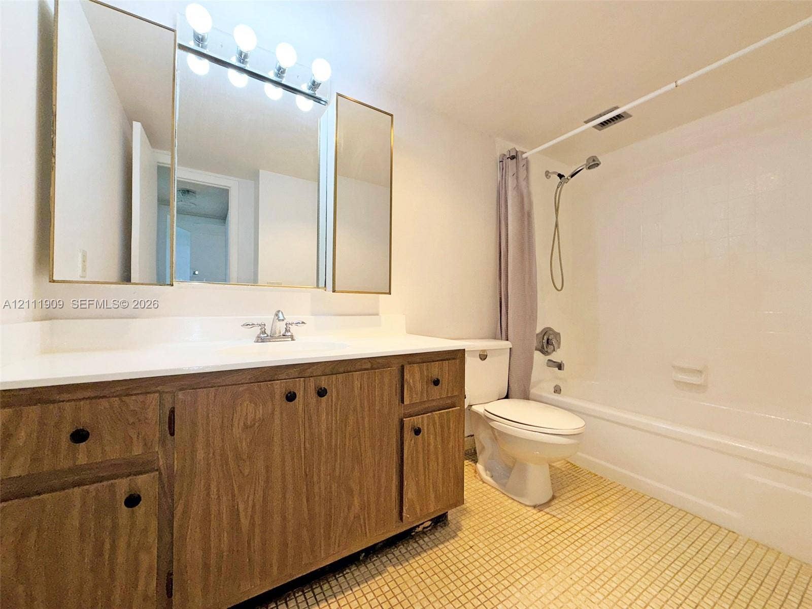 2851 NE 183rd Street, #1708E, Aventura, FL 33160 Bathroom featuring a wood-finish vanity with a white countertop, three-section mirrored medicine cabinet, integrated shower and tub enclosure, and ceramic tile flooring