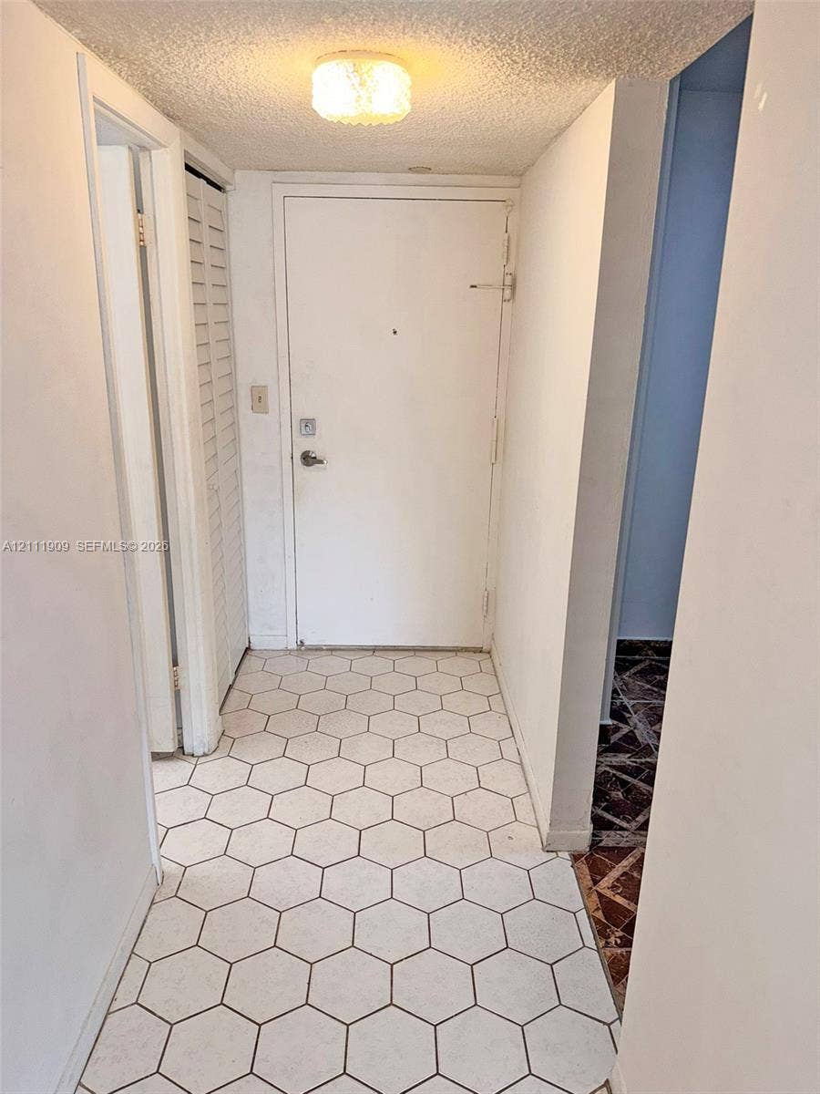 2851 NE 183rd Street, #1708E, Aventura, FL 33160 Entryway featuring white hexagonal floor tiling, a flush-mount drum ceiling light, and white paneled interior doors
