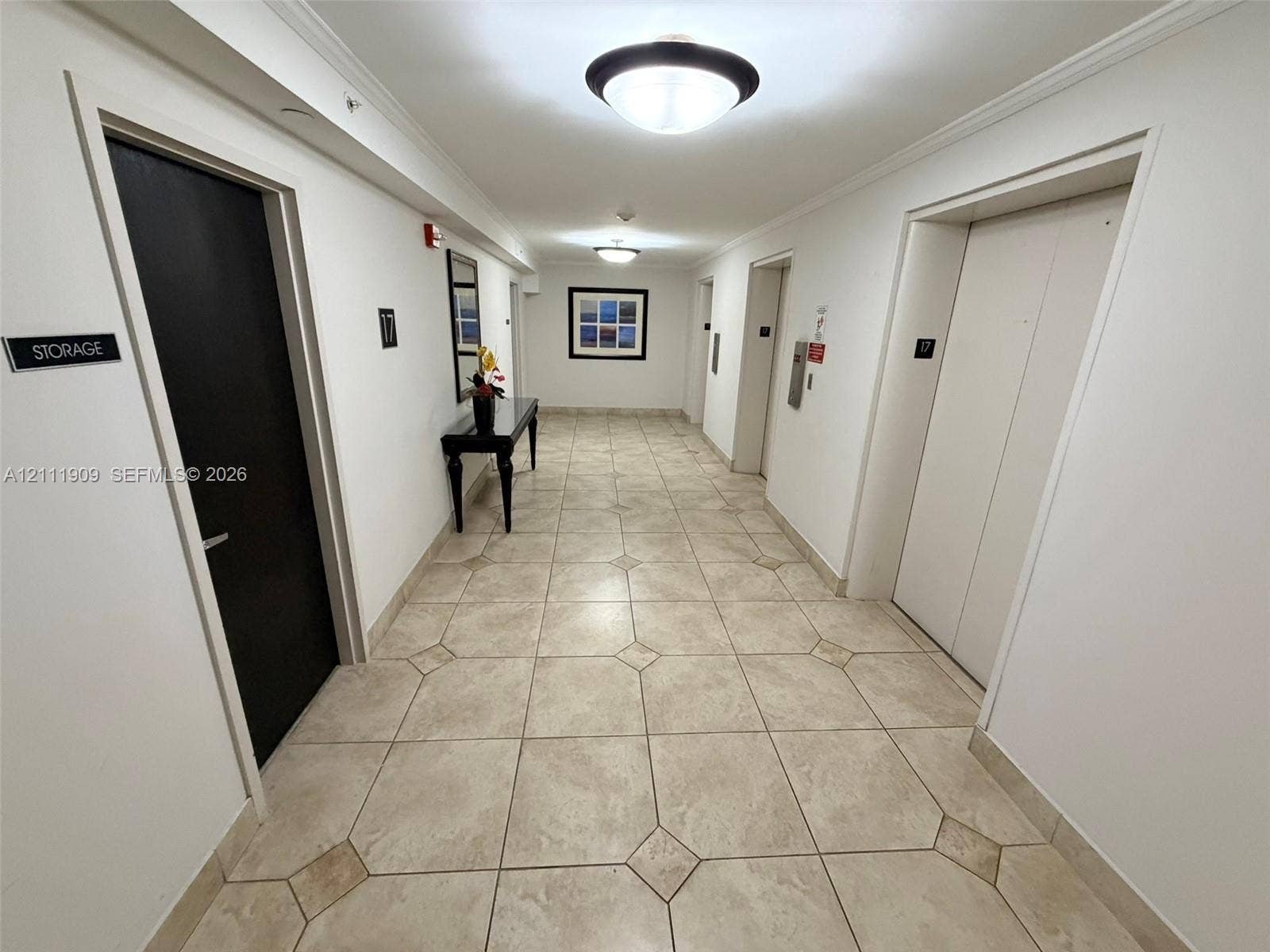 2851 NE 183rd Street, #1708E, Aventura, FL 33160 Hallway featuring neutral tile flooring with diamond-patterned inlay, ceiling-mounted dome lighting, and multiple elevator access points