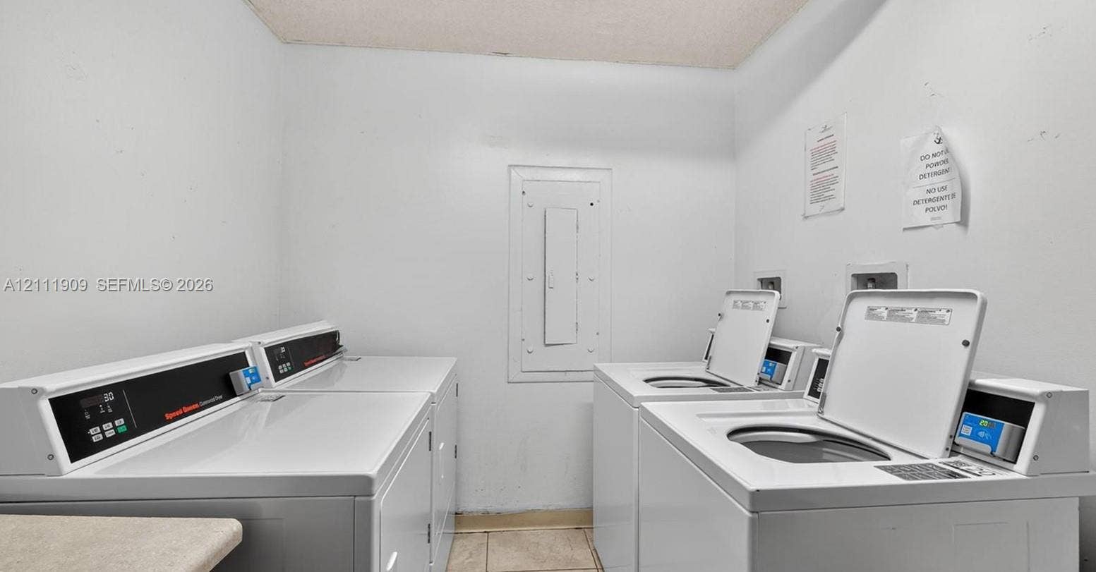 2851 NE 183rd Street, #1708E, Aventura, FL 33160 Laundry room featuring multiple high-capacity commercial-grade top-load washers and dryers and neutral tile flooring