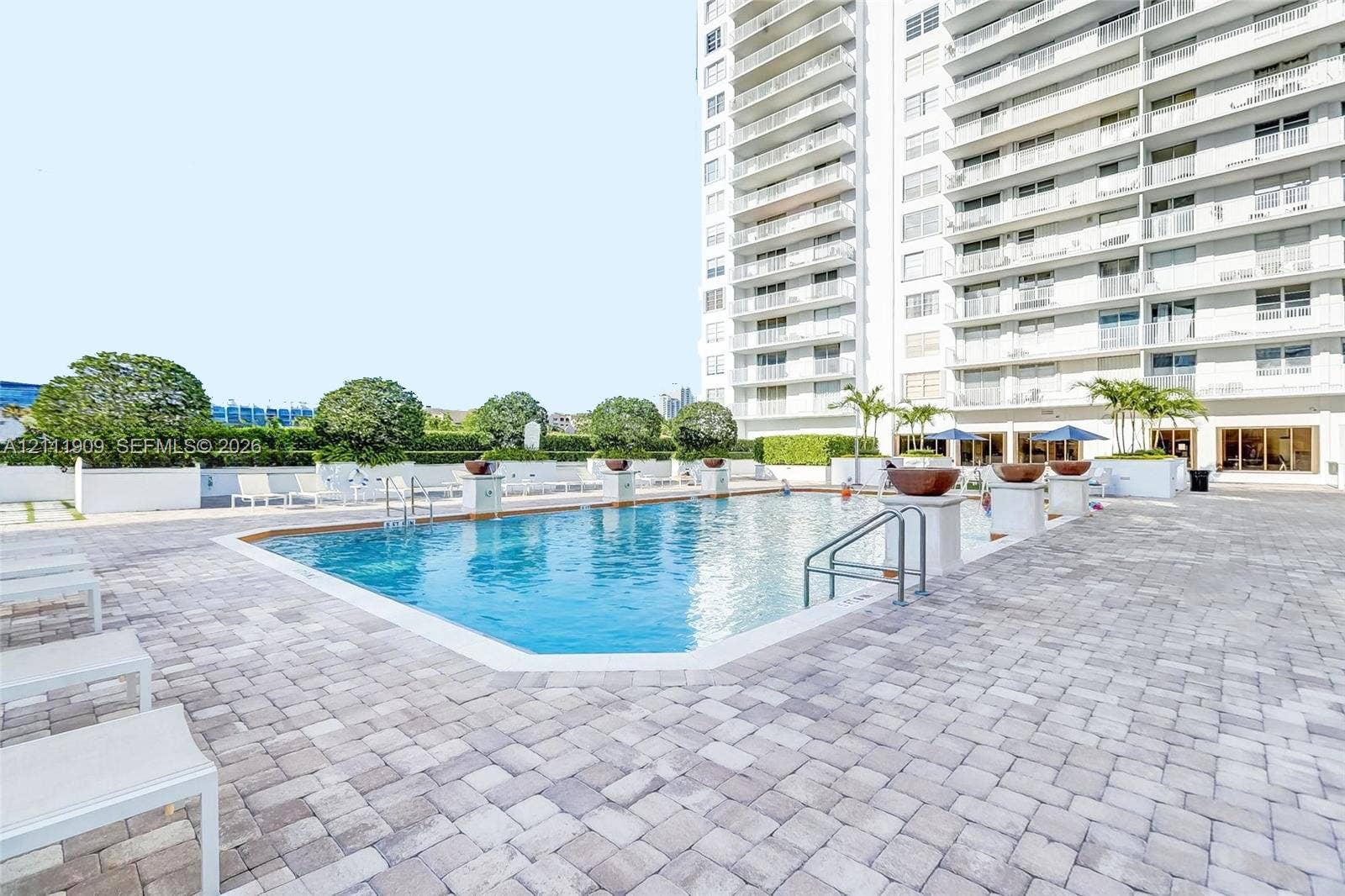 2851 NE 183rd Street, #1708E, Aventura, FL 33160 Swimming pool with metallic handrails, surrounding paver decking, and decorative stone planters