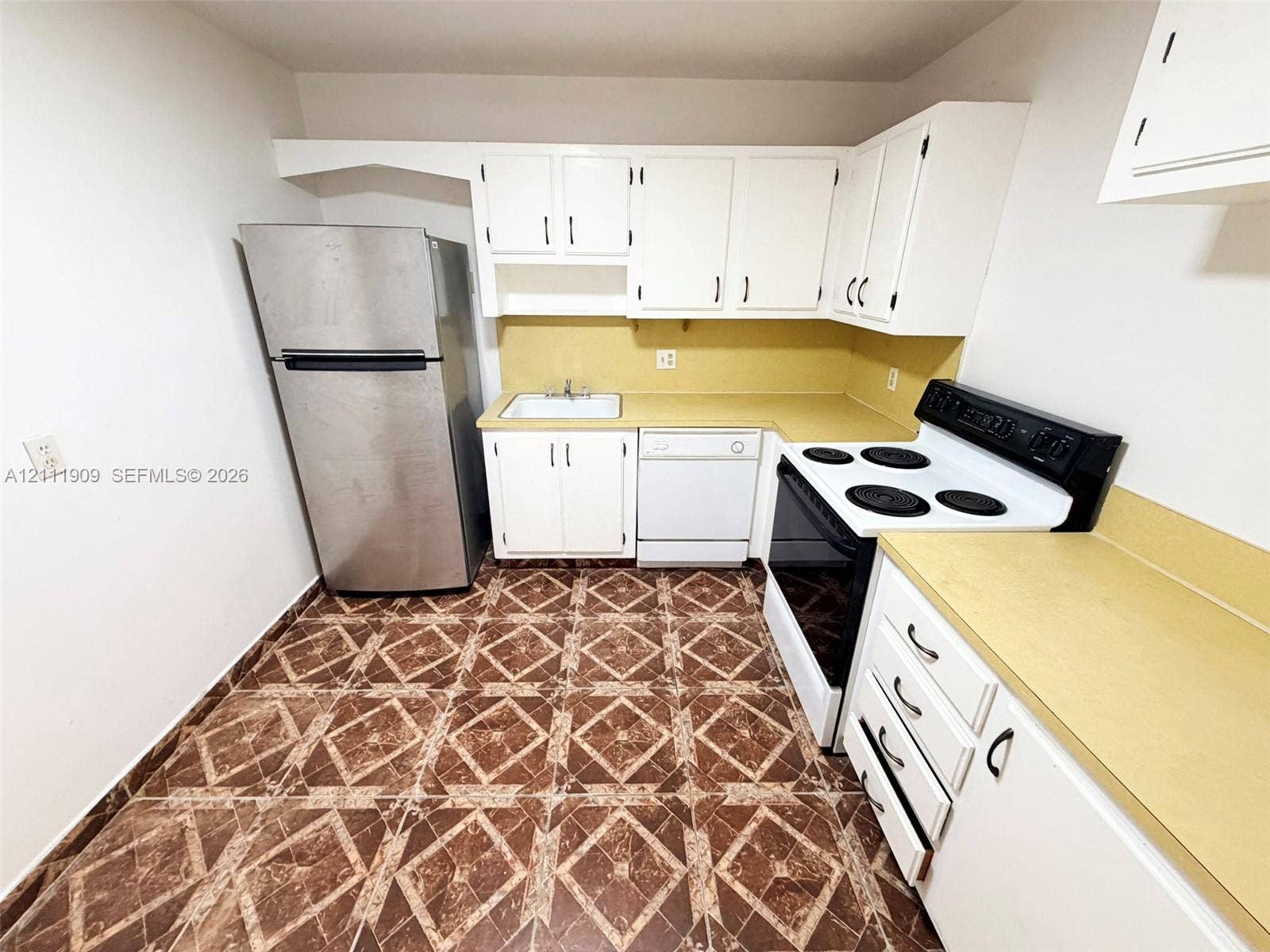 2851 NE 183rd Street, #1708E, Aventura, FL 33160 Kitchen featuring white cabinetry, solid-surface countertops, tile flooring, and integrated appliances