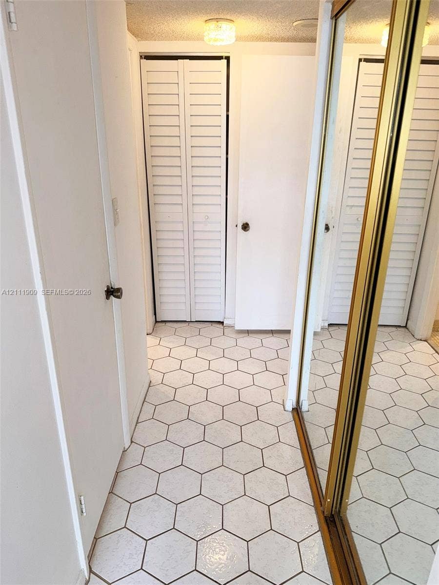 2851 NE 183rd Street, #1708E, Aventura, FL 33160 Hexagon tile flooring, white louvered bifold doors, and sliding mirrored closet doors with gold-tone metal frames
