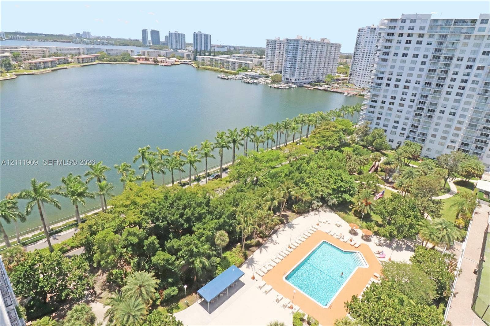 2851 NE 183rd Street, #1708E, Aventura, FL 33160 Elevated aerial perspective featuring a waterfront location, expansive lake, swimming pool with deck, mature landscaping, and palm trees