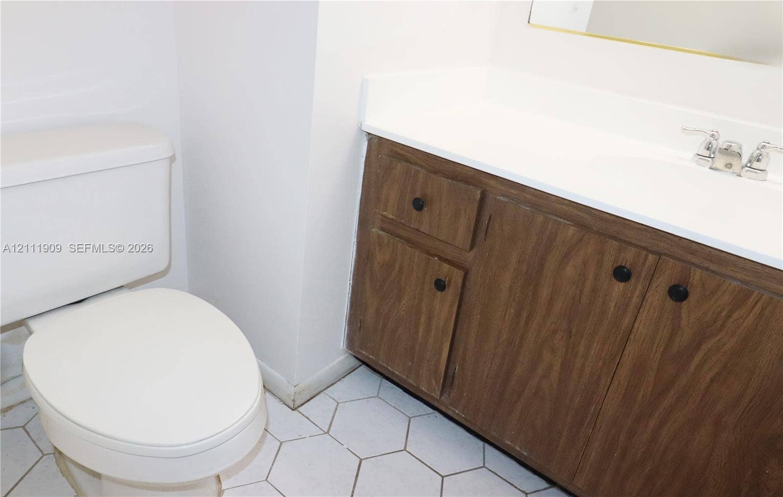2851 NE 183rd Street, #1708E, Aventura, FL 33160 Bathroom featuring a wood-finish vanity with a white countertop, integrated sink, chrome dual-handle faucet, and white hexagonal floor tiling