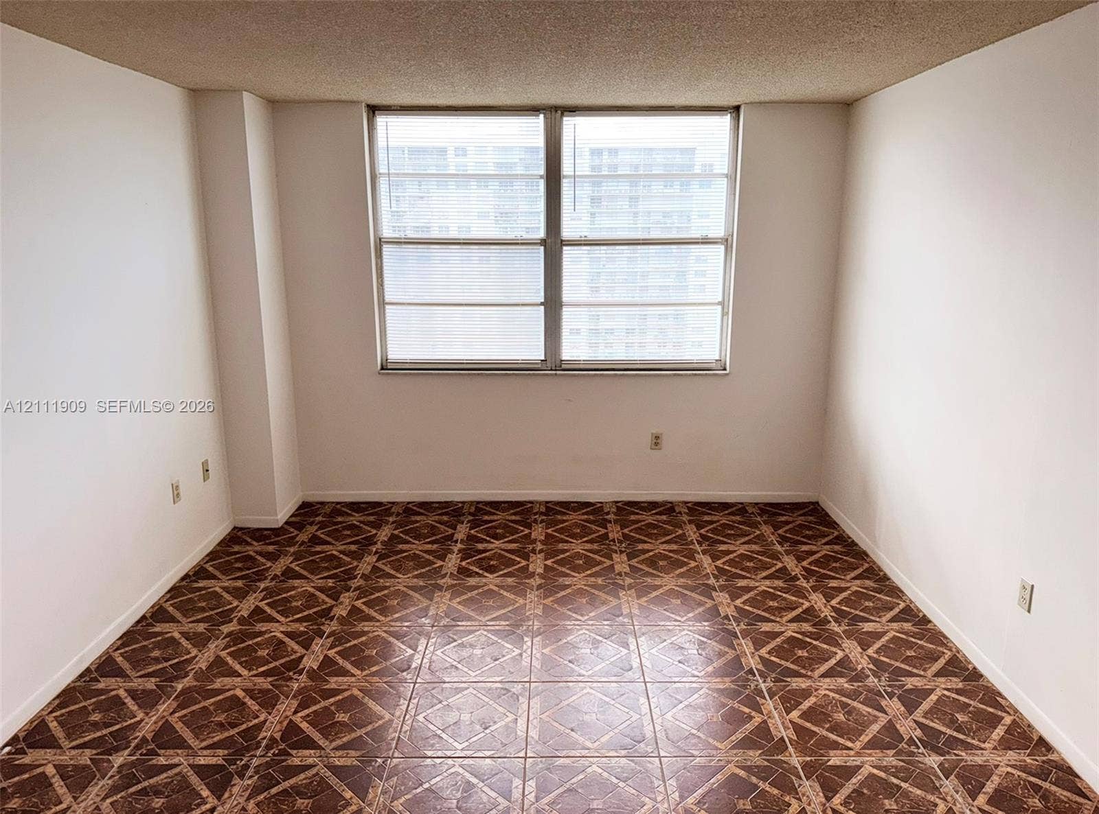 2851 NE 183rd Street, #1708E, Aventura, FL 33160 Interior space featuring patterned tile flooring, textured ceiling, and a large dual-pane window