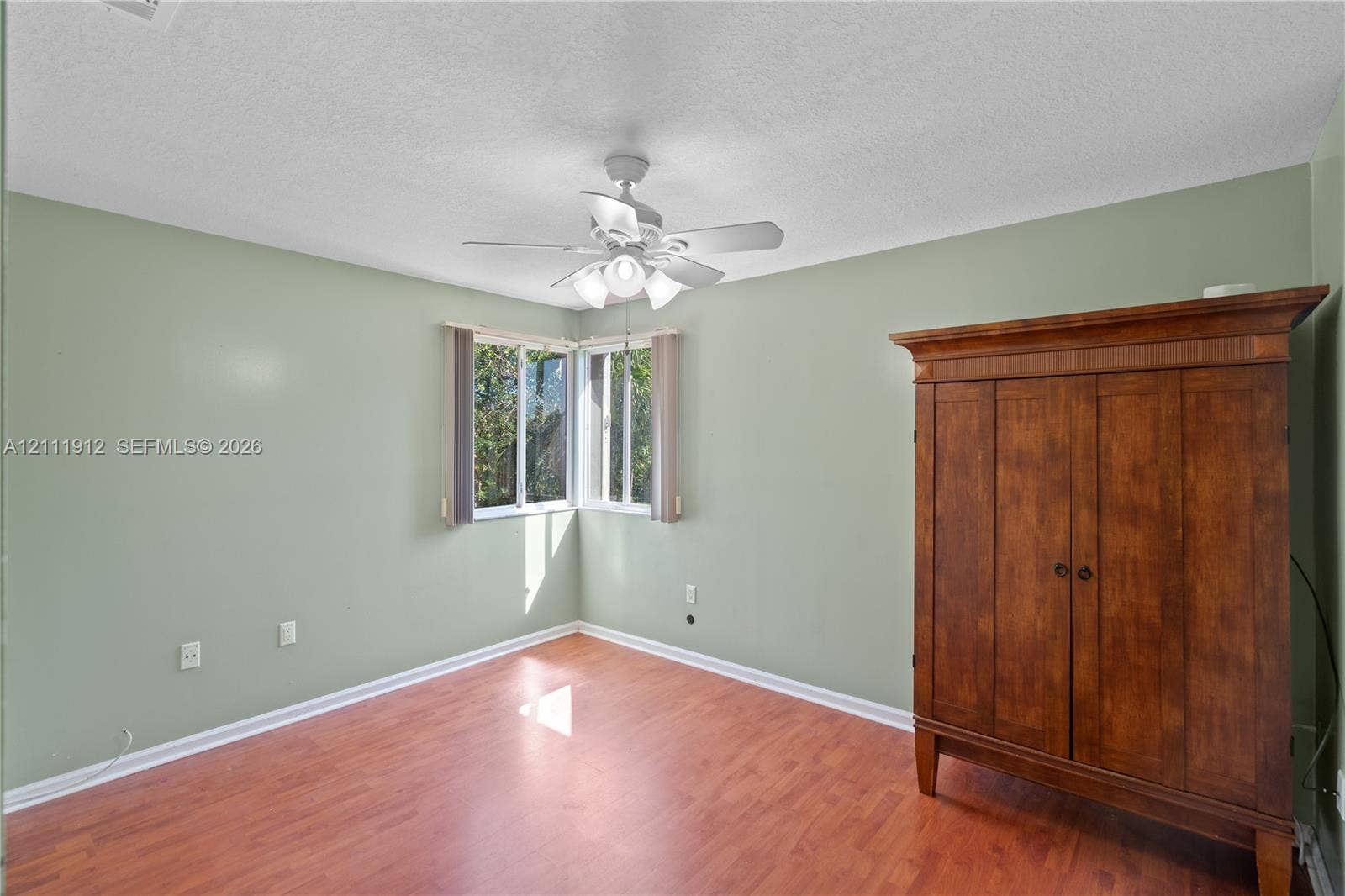 15681 SW 147th Court, Miami, FL 33187 Interior space featuring wood-finish flooring, corner windows, and a ceiling-mounted light fixture with a fan
