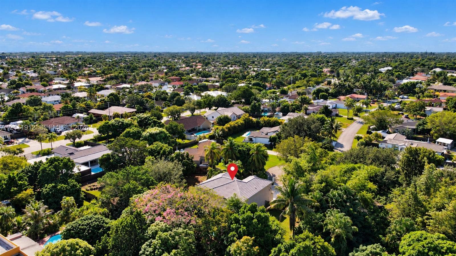 15681 SW 147th Court, Miami, FL 33187 Aerial perspective featuring a low-slope roof structure surrounded by mature trees and dense residential landscape