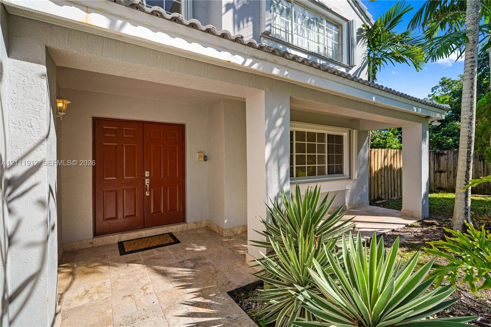 15681 SW 147th Court, Miami, FL 33187 Covered front porch featuring natural stone flooring, double entry doors, stucco exterior walls, and tiled roof architecture