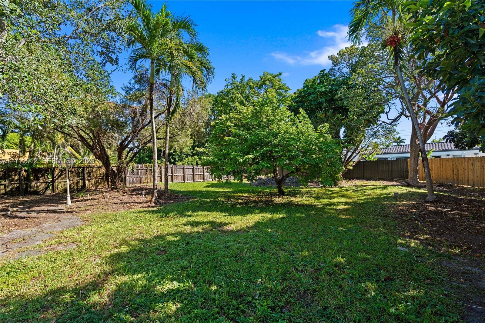 15681 SW 147th Court, Miami, FL 33187 Expansive backyard featuring mature palm and hardwood trees, grass lawn, and perimeter wood fencing