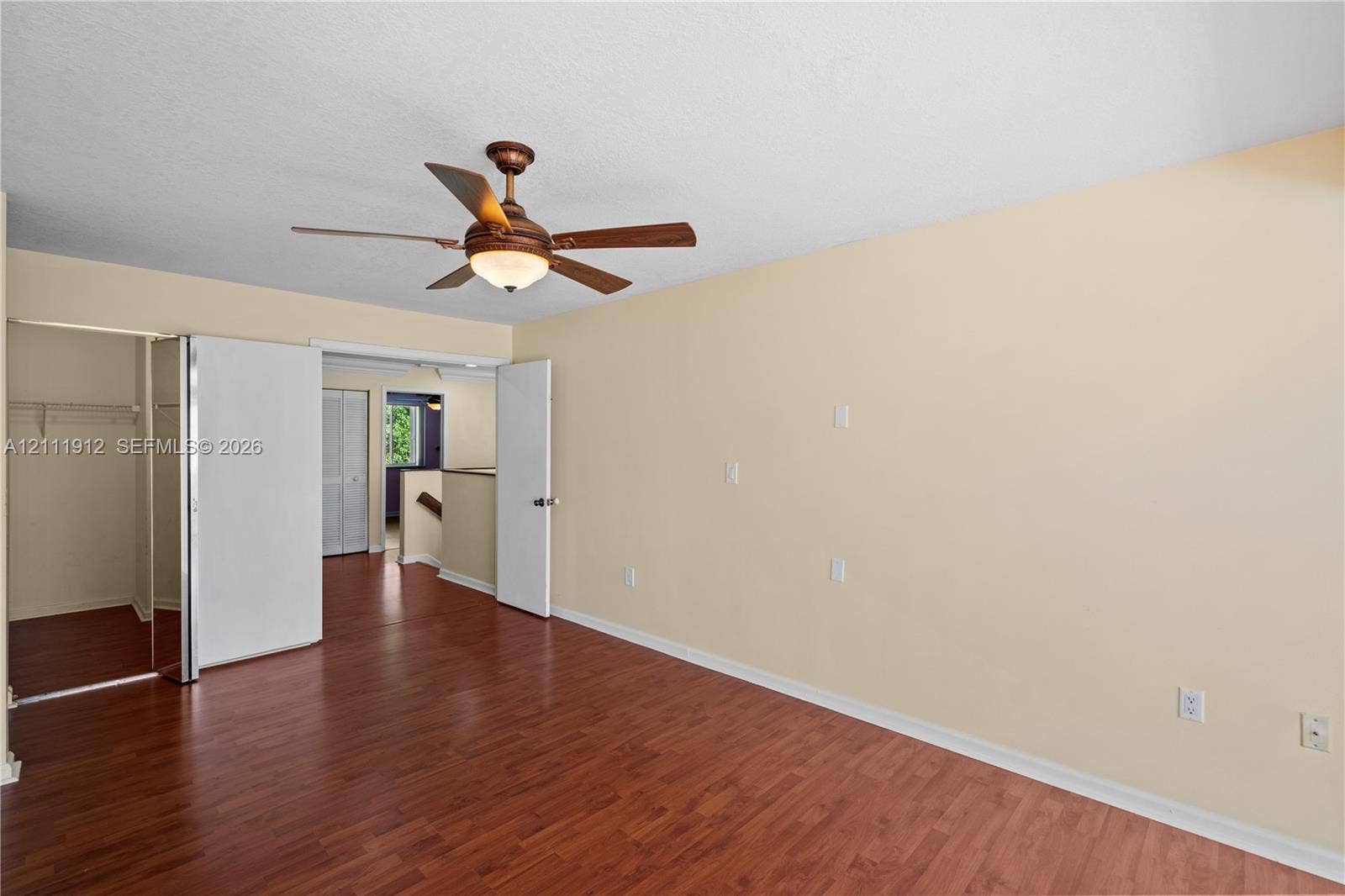 15681 SW 147th Court, Miami, FL 33187 Room featuring wood-finish flooring, a ceiling fan with integrated lighting, and a closet with mirrored doors