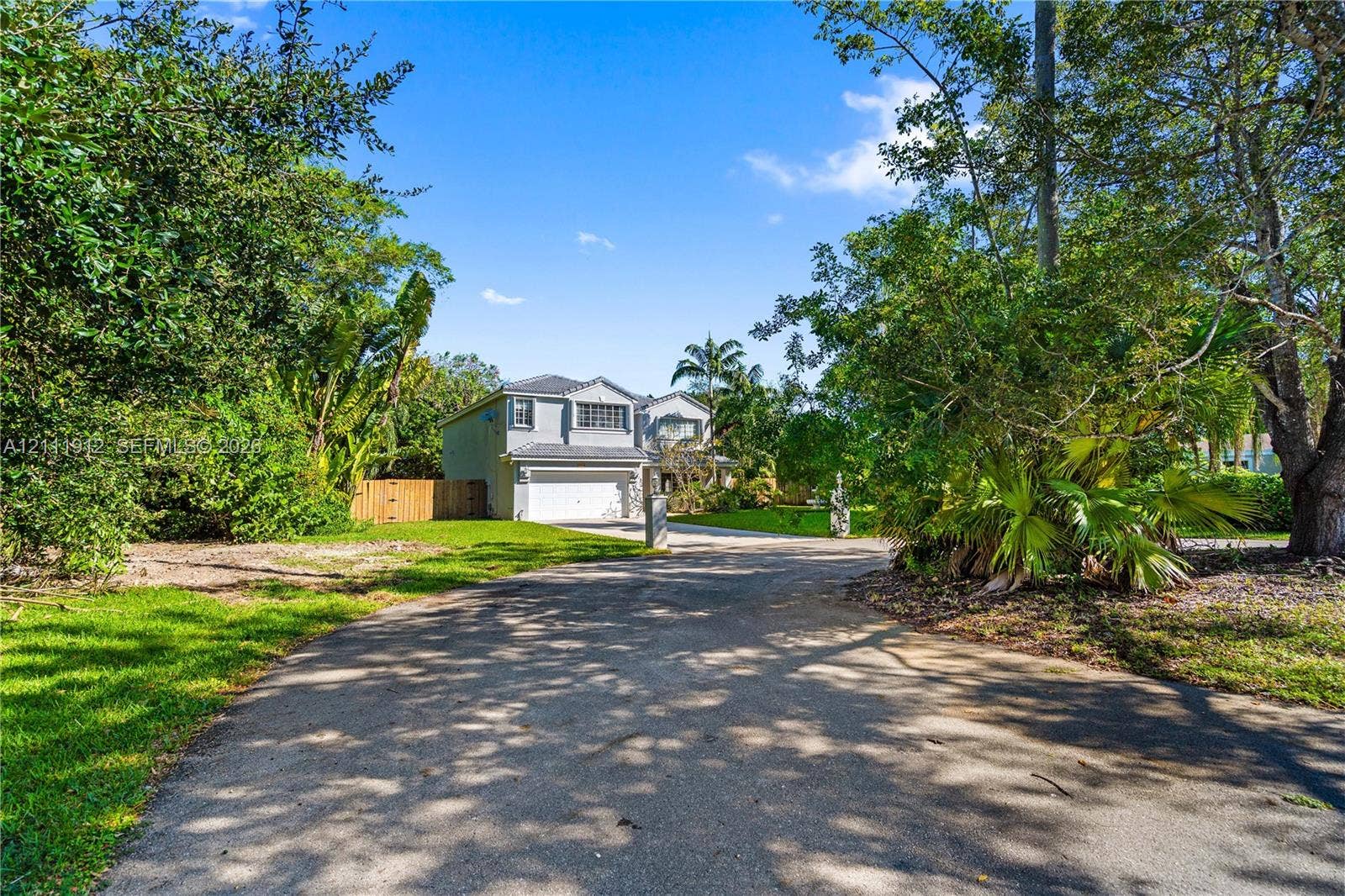 15681 SW 147th Court, Miami, FL 33187 Two-story residence featuring a multi-gabled roofline, an attached two-car garage, an asphalt driveway, and mature landscaping