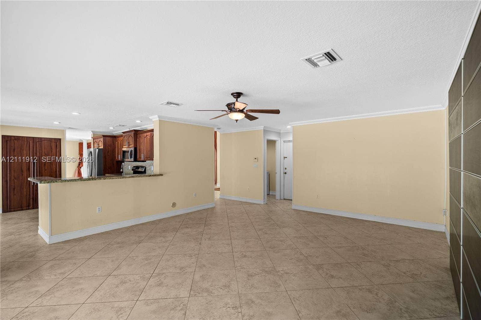 15681 SW 147th Court, Miami, FL 33187 Interior space featuring tile flooring, ceiling-mounted fan, stone-surfaced kitchen breakfast bar, and dark wood-finish cabinetry