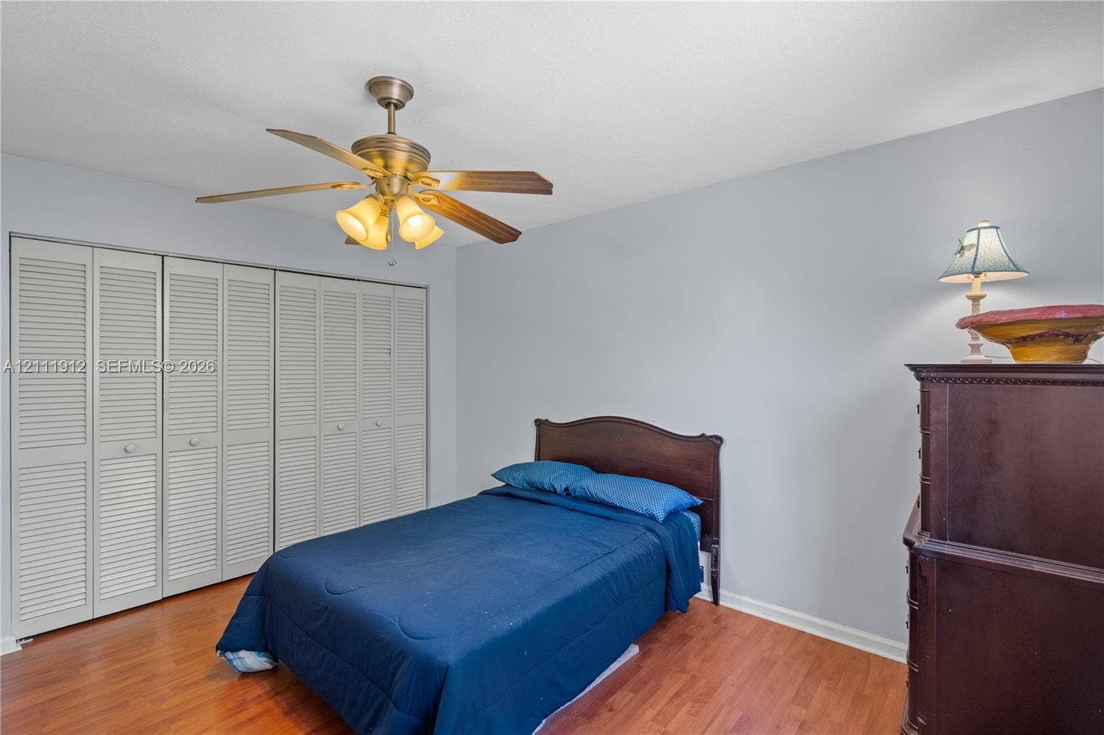 15681 SW 147th Court, Miami, FL 33187 Room featuring wood-finish flooring, floor-to-ceiling louvered closet doors, and a multi-light ceiling fan