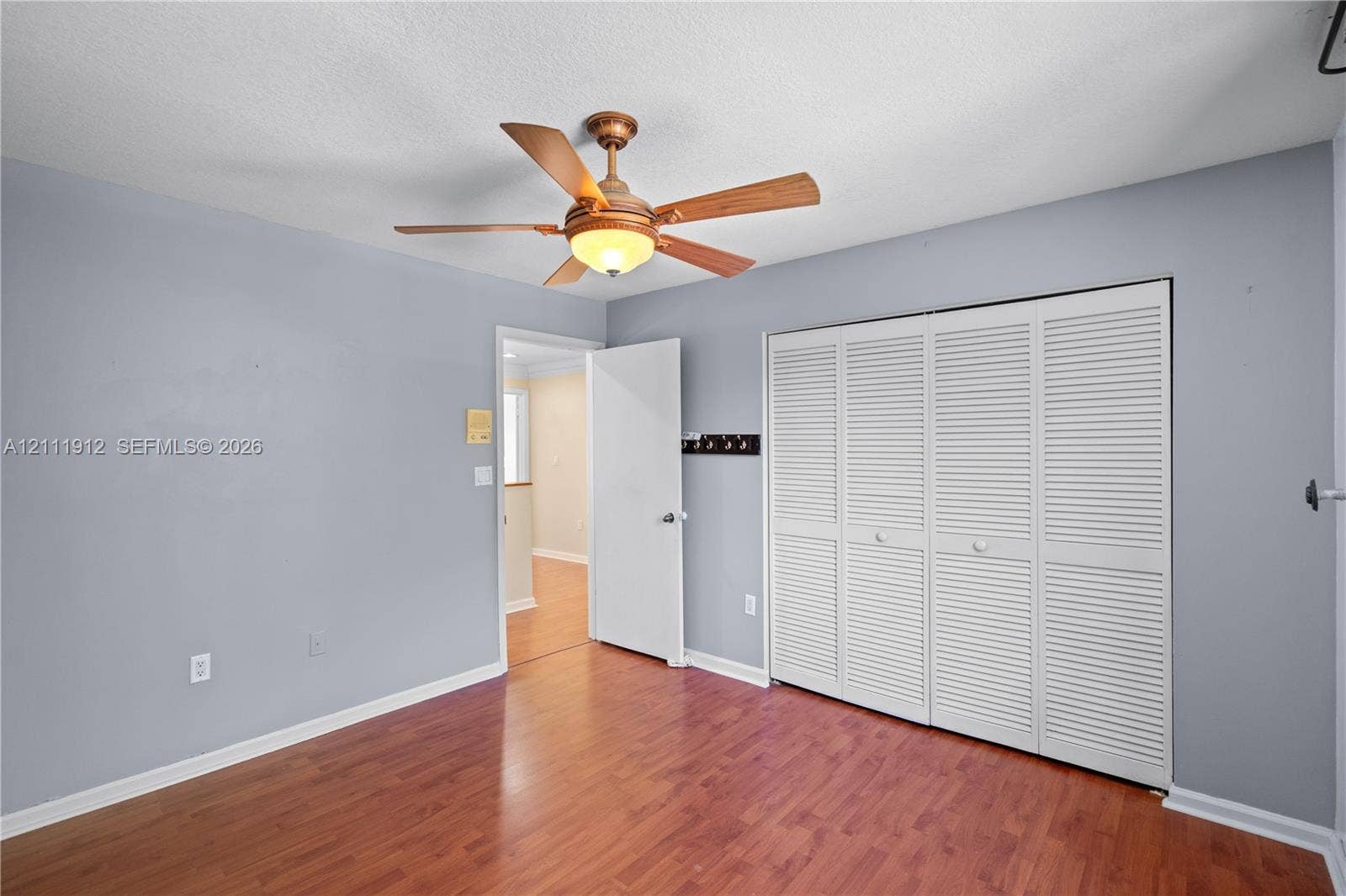 15681 SW 147th Court, Miami, FL 33187 Room featuring wood-finish flooring, a ceiling fan with integrated lighting, and a four-panel louvered closet door