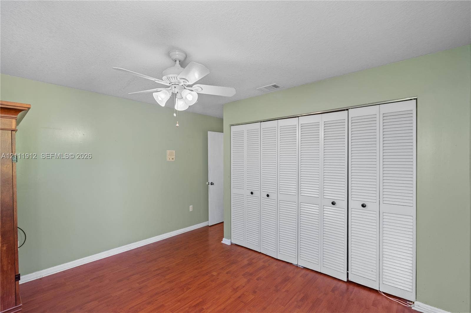 15681 SW 147th Court, Miami, FL 33187 Wood-finish flooring, white louvered bifold closet doors, and a ceiling fan with integrated multi-light fixture