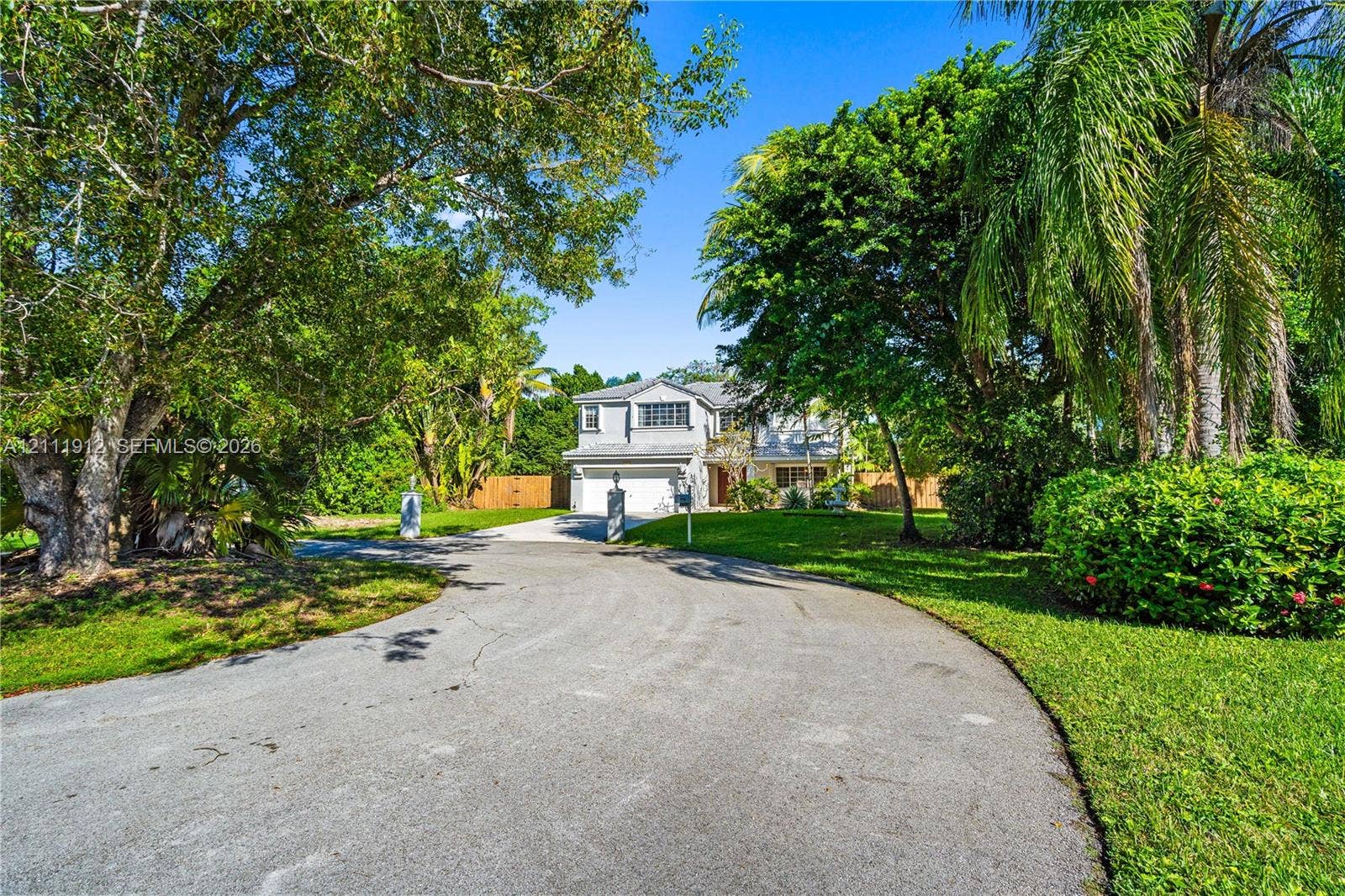 15681 SW 147th Court, Miami, FL 33187 Two-story residence featuring a paved circular driveway, sprawling lawn, mature trees, and attached garage