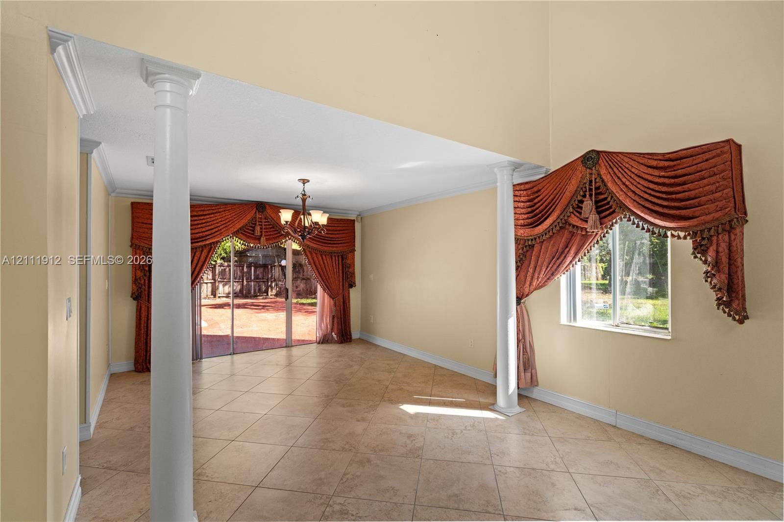 15681 SW 147th Court, Miami, FL 33187 Interior space featuring high ceilings, large-format tile flooring, decorative architectural columns, and sliding glass doors