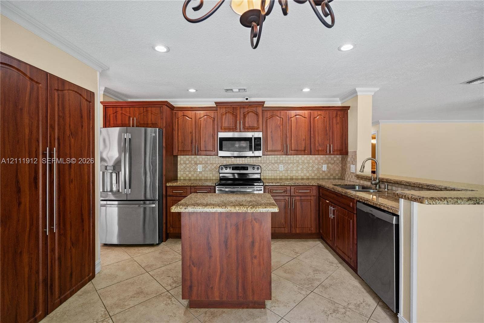 15681 SW 147th Court, Miami, FL 33187 Kitchen featuring cherry-finish cabinetry, stainless steel appliances, stone-surface countertops, a center island, and tile flooring