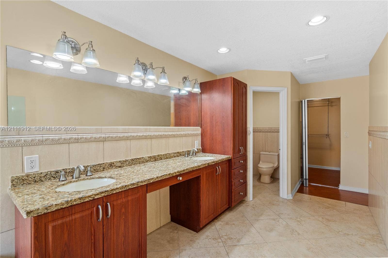 15681 SW 147th Court, Miami, FL 33187 Bathroom featuring a dual-sink vanity with stone countertop, wood-finish cabinetry, full-width wall mirror, and tile flooring