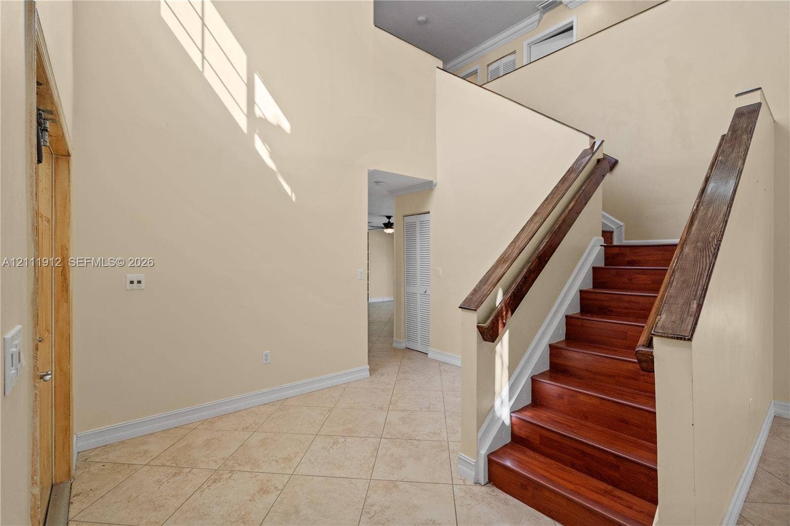 15681 SW 147th Court, Miami, FL 33187 High-ceiling foyer featuring tile flooring, a staircase with wood-finish treads, and a custom wood handrail
