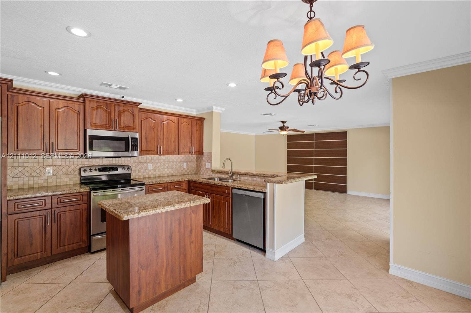 15681 SW 147th Court, Miami, FL 33187 Kitchen featuring wood cabinetry, stone-finish countertops, stainless steel appliances, a center island, and a multi-arm chandelier