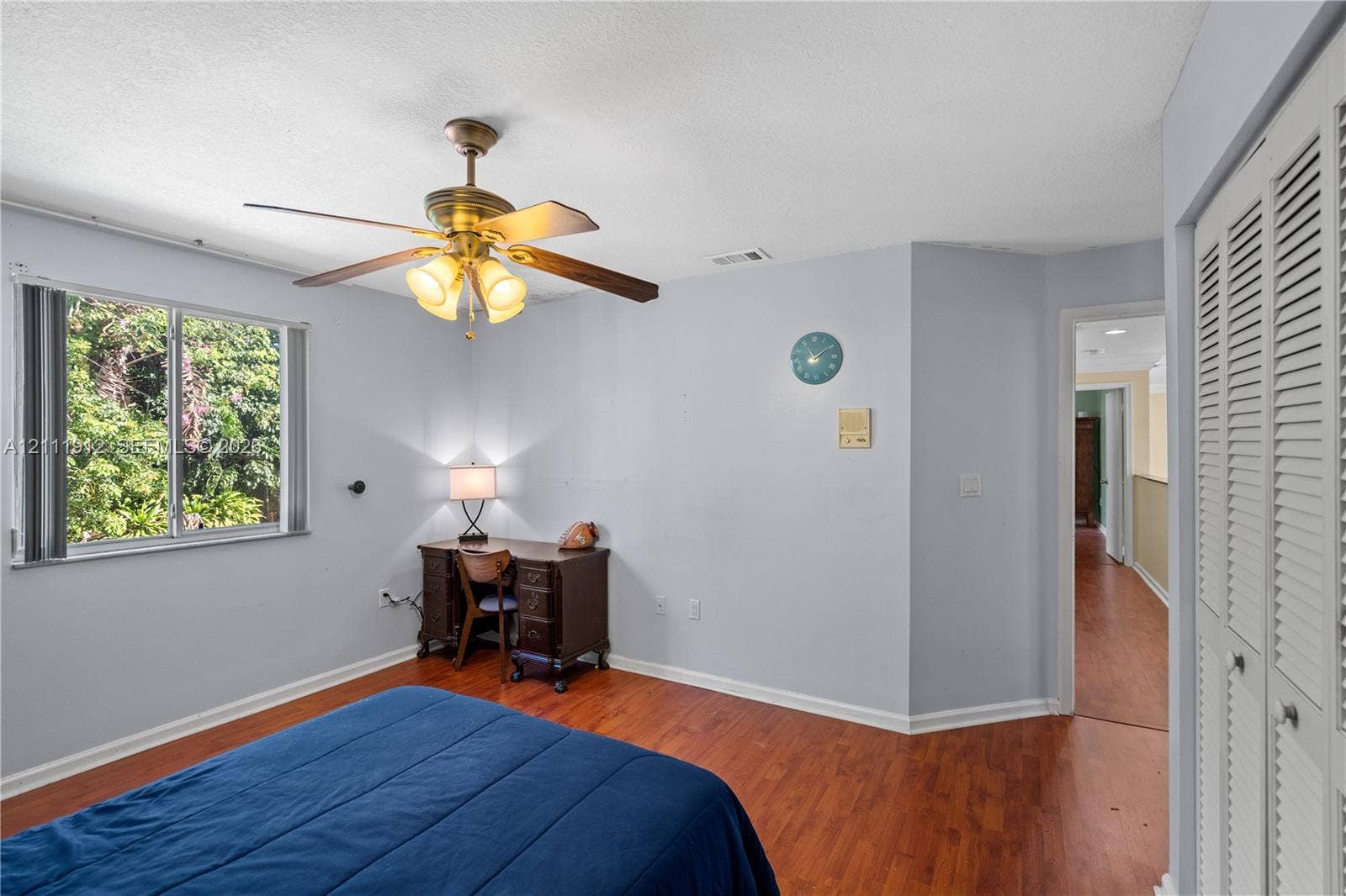 15681 SW 147th Court, Miami, FL 33187 Room with wood-finish flooring, ceiling fan with integrated lighting, dual-pane window, and louvered bi-fold closet doors