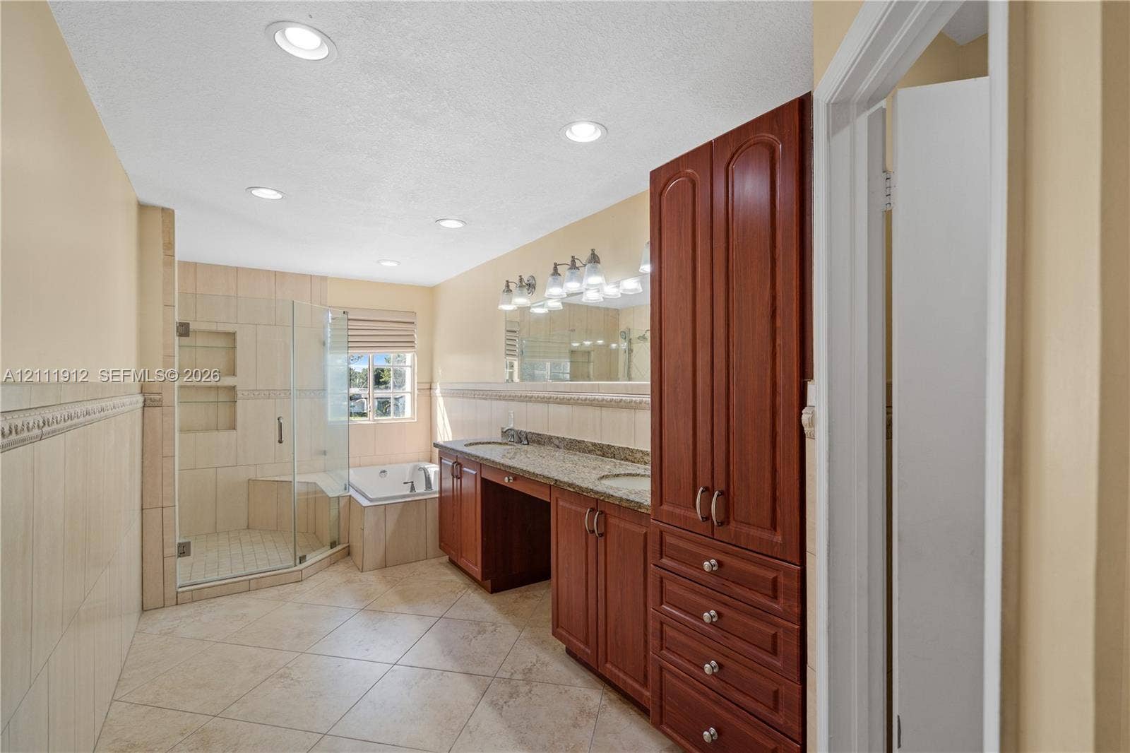 15681 SW 147th Court, Miami, FL 33187 Bathroom featuring tile flooring, a dual-sink vanity with stone countertop, built-in floor-to-ceiling cabinetry, a tiled walk-in shower with glass enclosure, and a built-in soaking tub