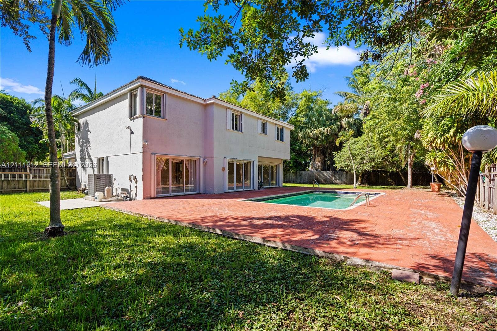 15681 SW 147th Court, Miami, FL 33187 Two-story exterior featuring a stucco facade, in-ground swimming pool, expansive paved patio, and mature landscaping